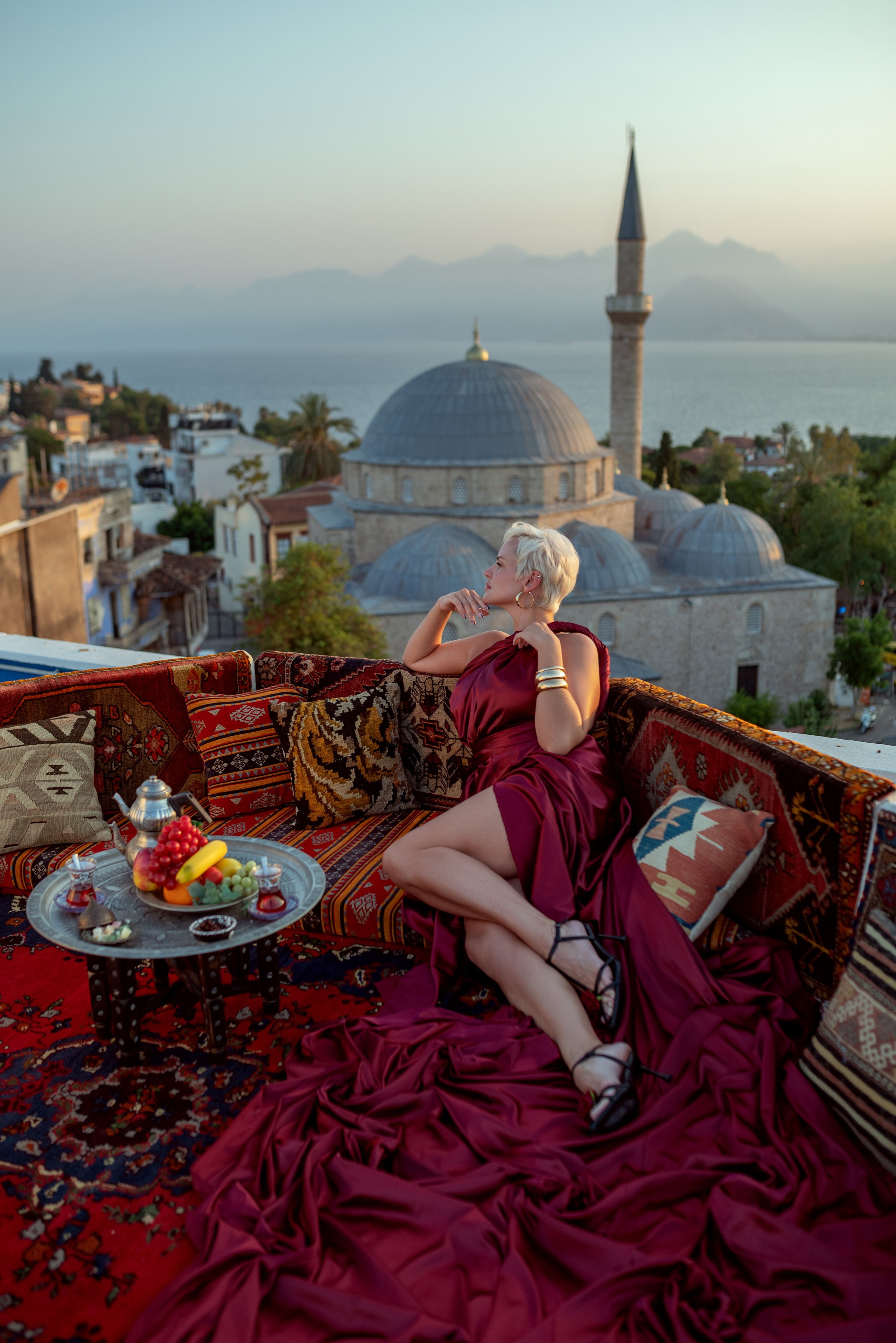 Фото девушки на крыше среди турецких ковров с видом на достопримечательности Анталия Турция