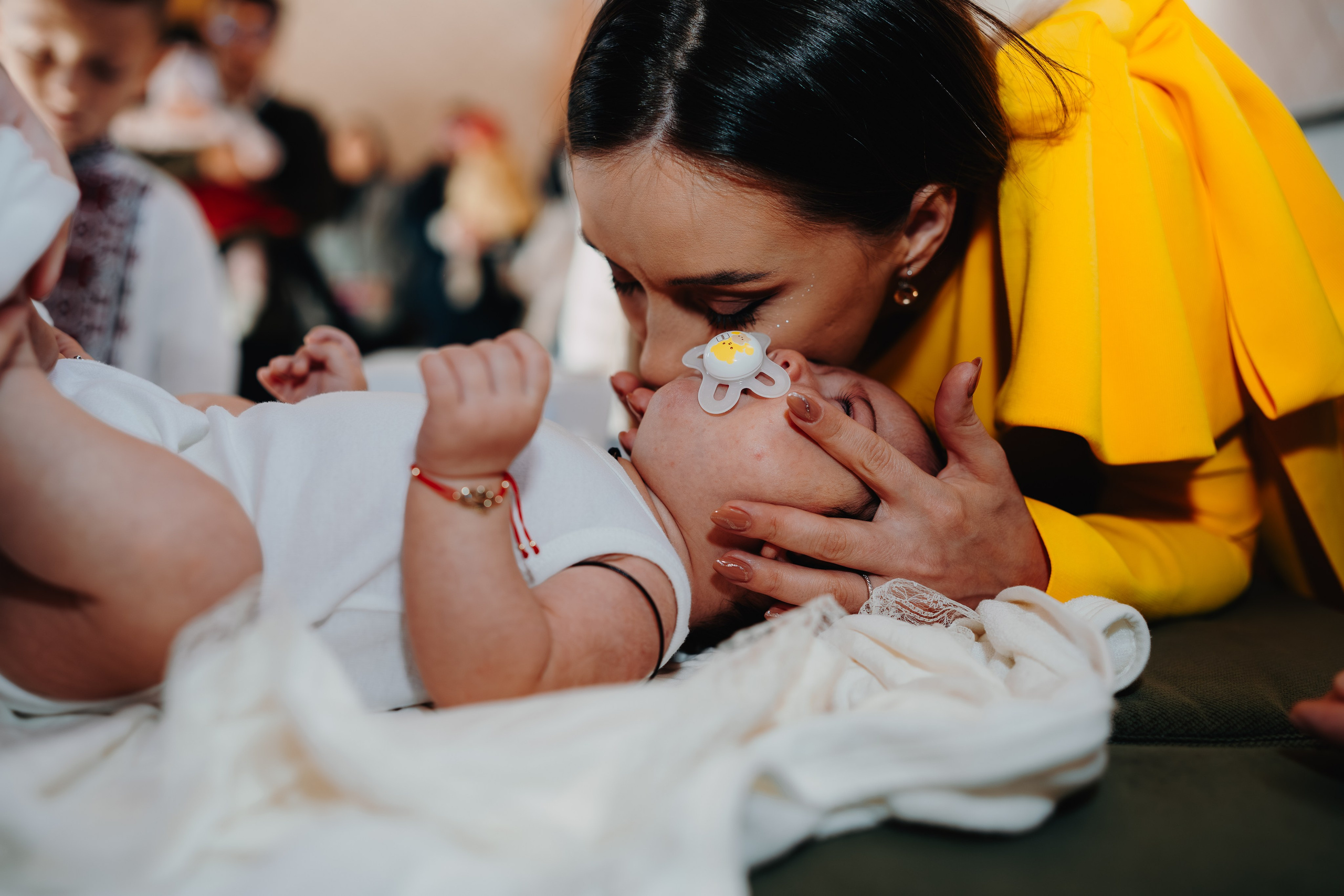 Un alt cadru intim din seria de calmare: mama și nașa lui Arthur Mihail rămân apropiate de el pe masa botezului, oferind prezență și liniște după un moment agitat. Fotografie naturală care evidențiază sprijinul și tandrețea.
