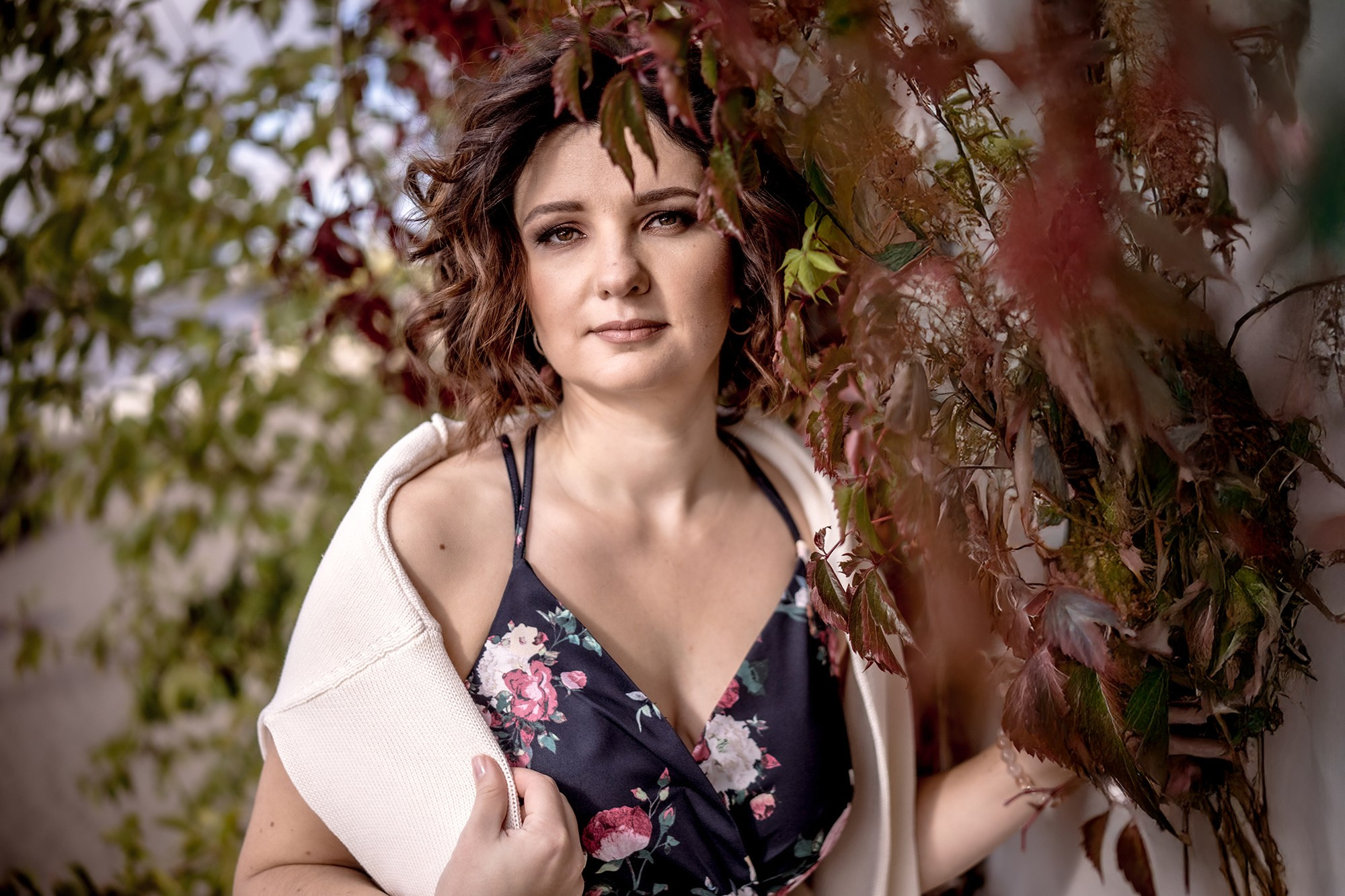 A beautiful woman standing next to branches of autumn grapes, Riga portrait photographer