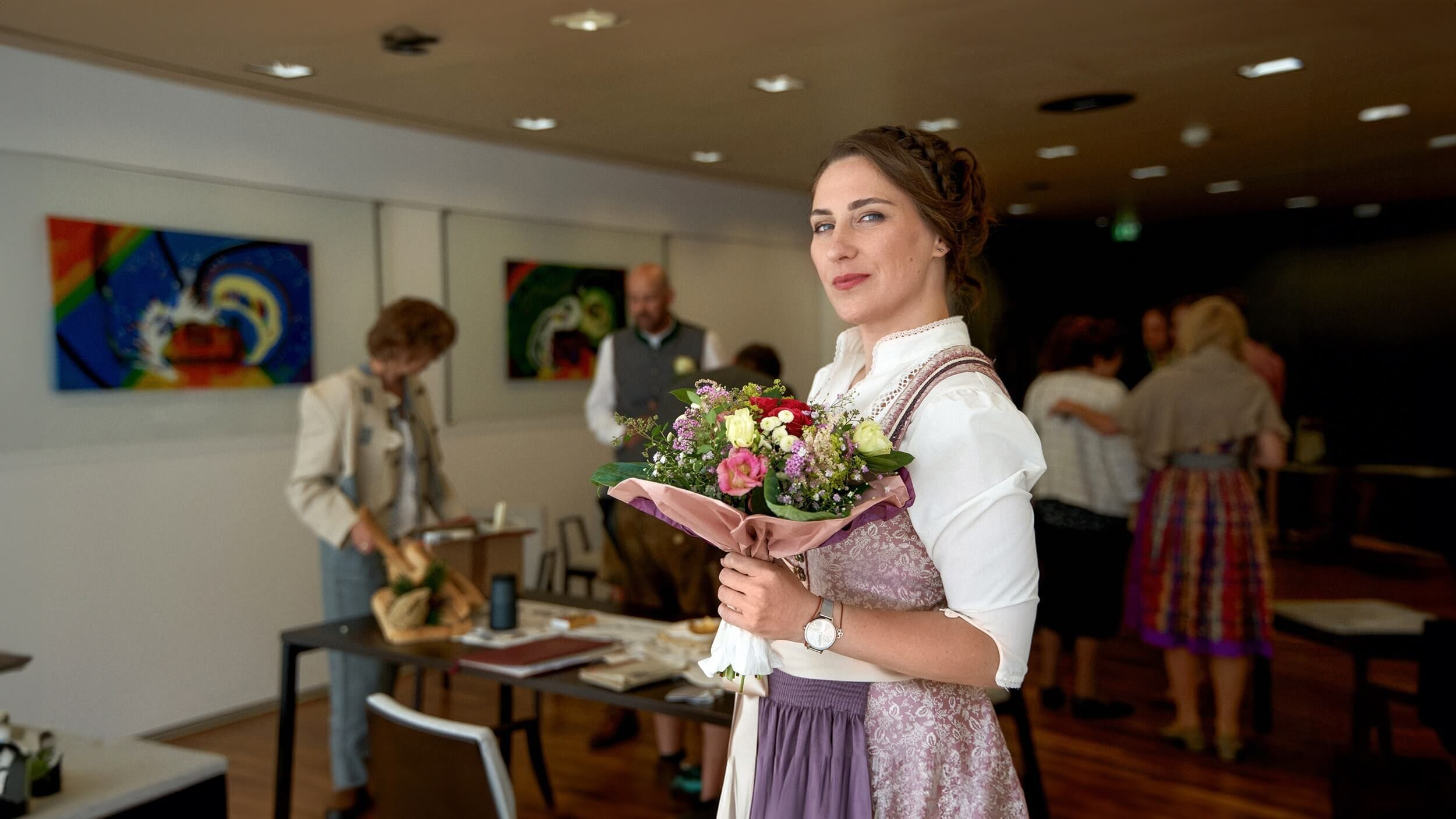 Frau mit Blumenstrauß und weitere Gäste im festlich geschmückten Standesamt Sölden während der Trauung.