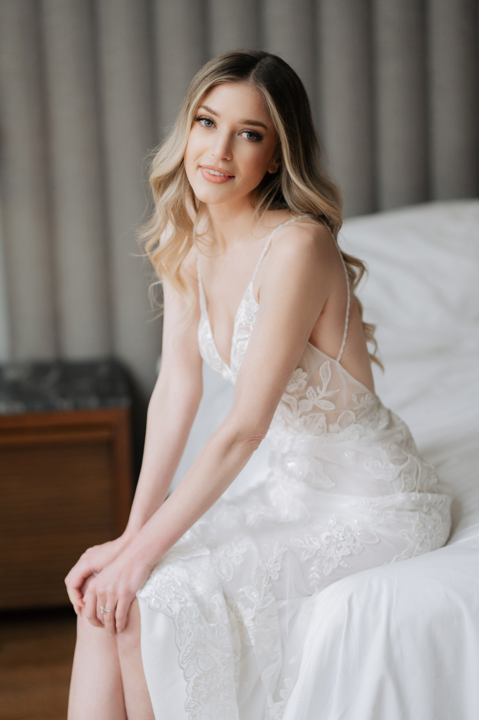 a woman in a white dress sitting on a bed
