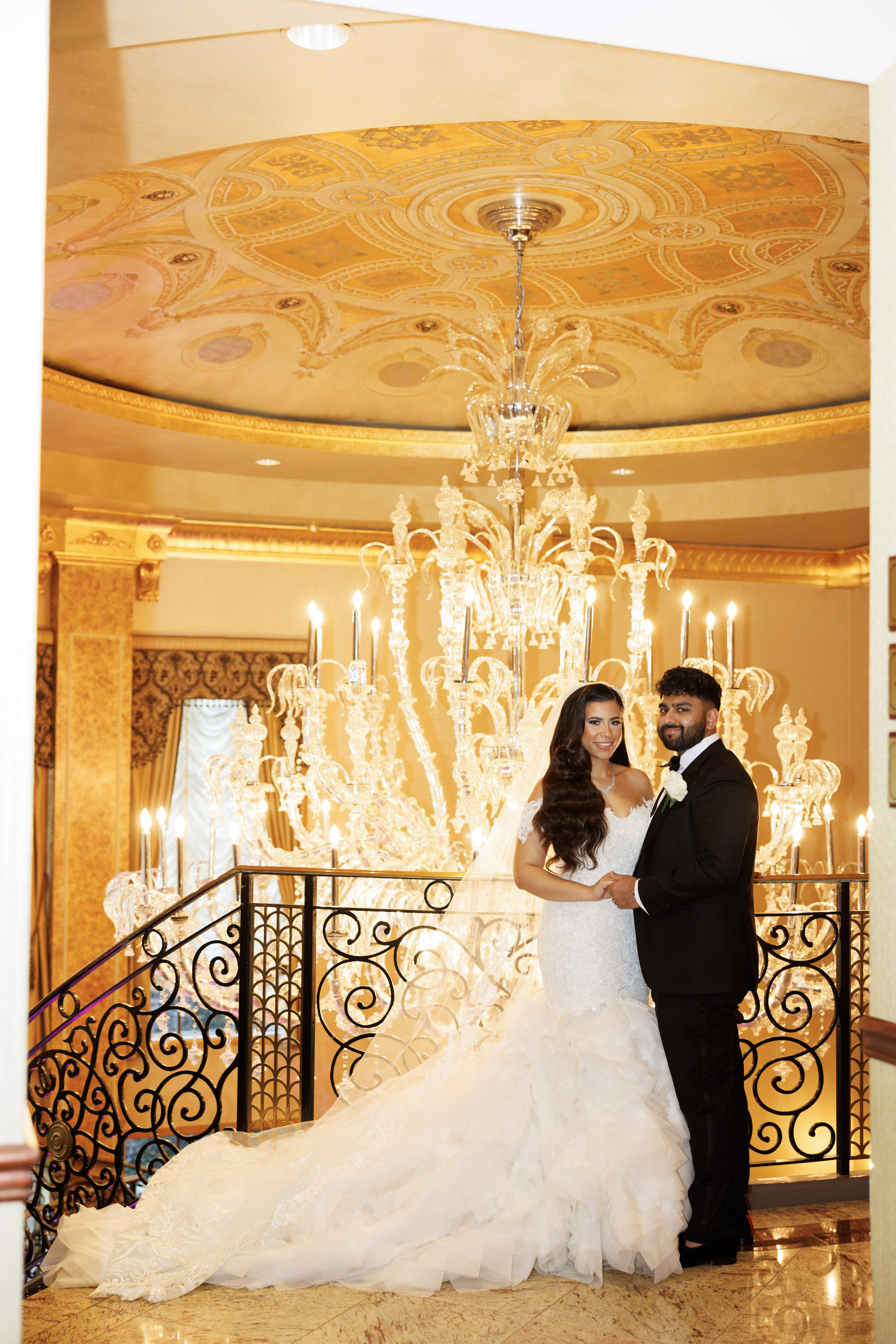a bride and groom pose for a photo in front of a chandel