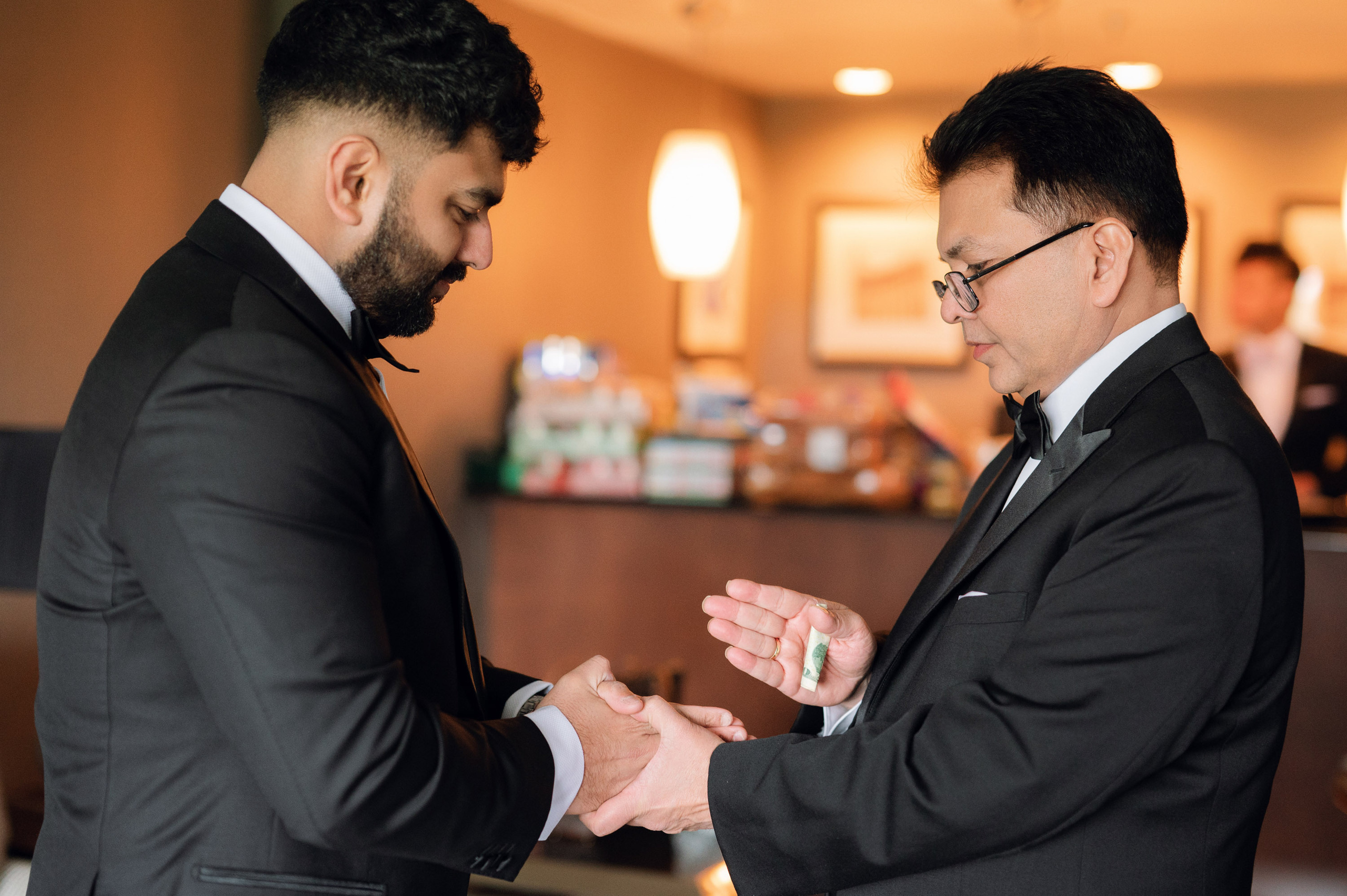 two men in suits are putting a ring on another man