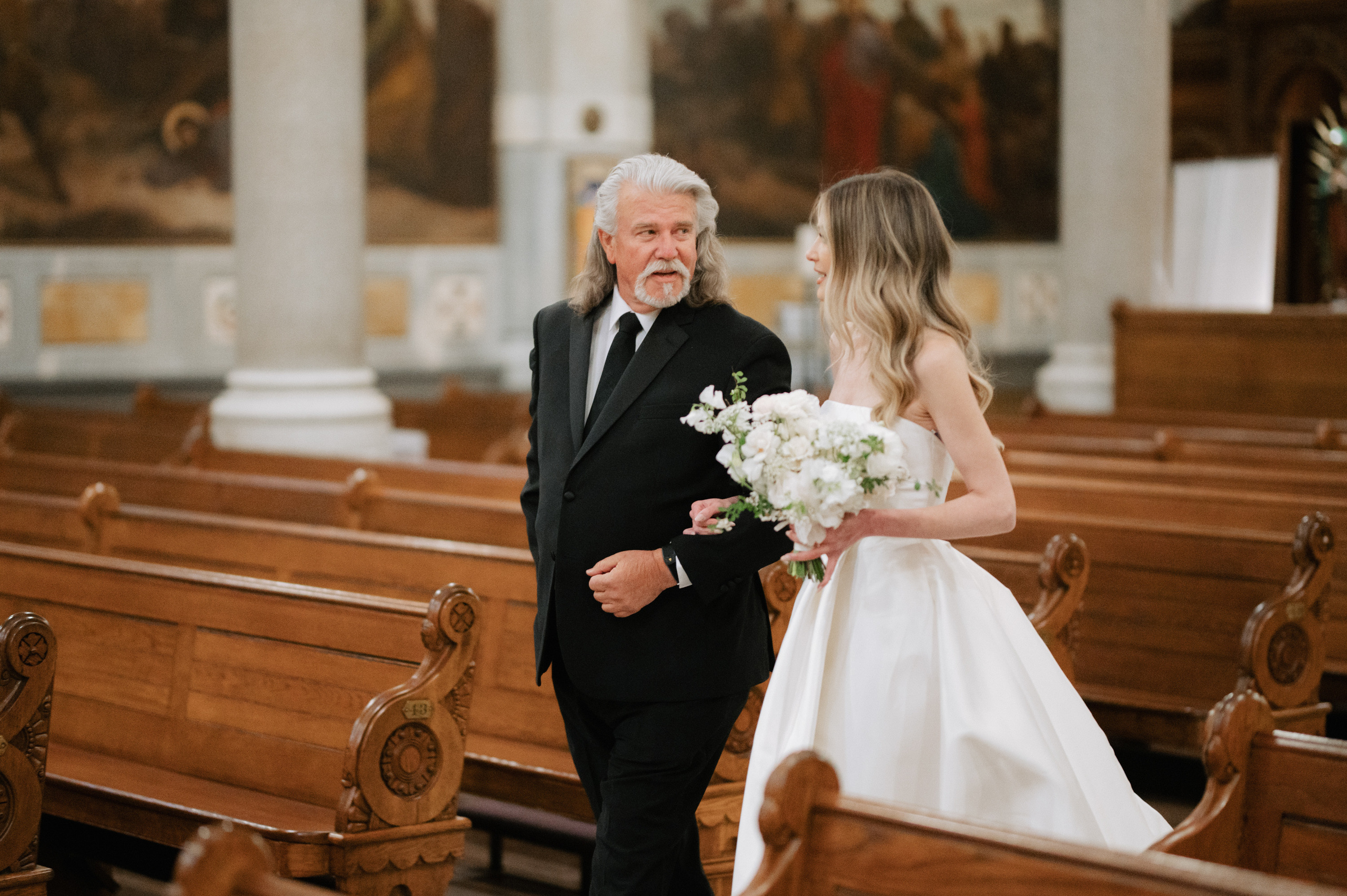 a man and woman walking down a church aisle