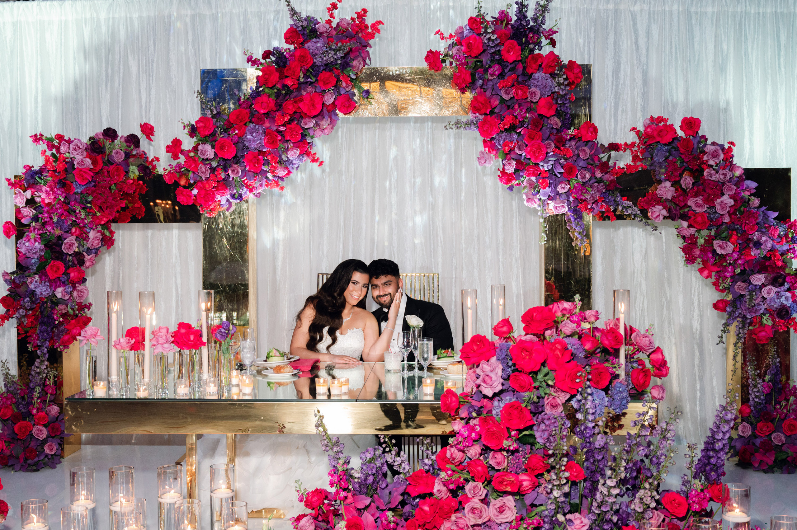 a couple sitting at a table with flowers and candles
