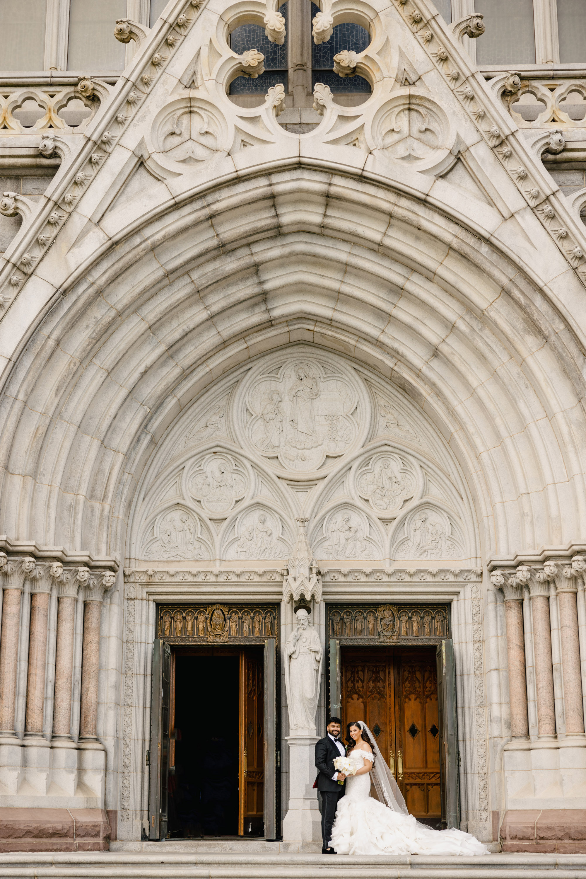 a bride and groom pose for a photo in front of a church