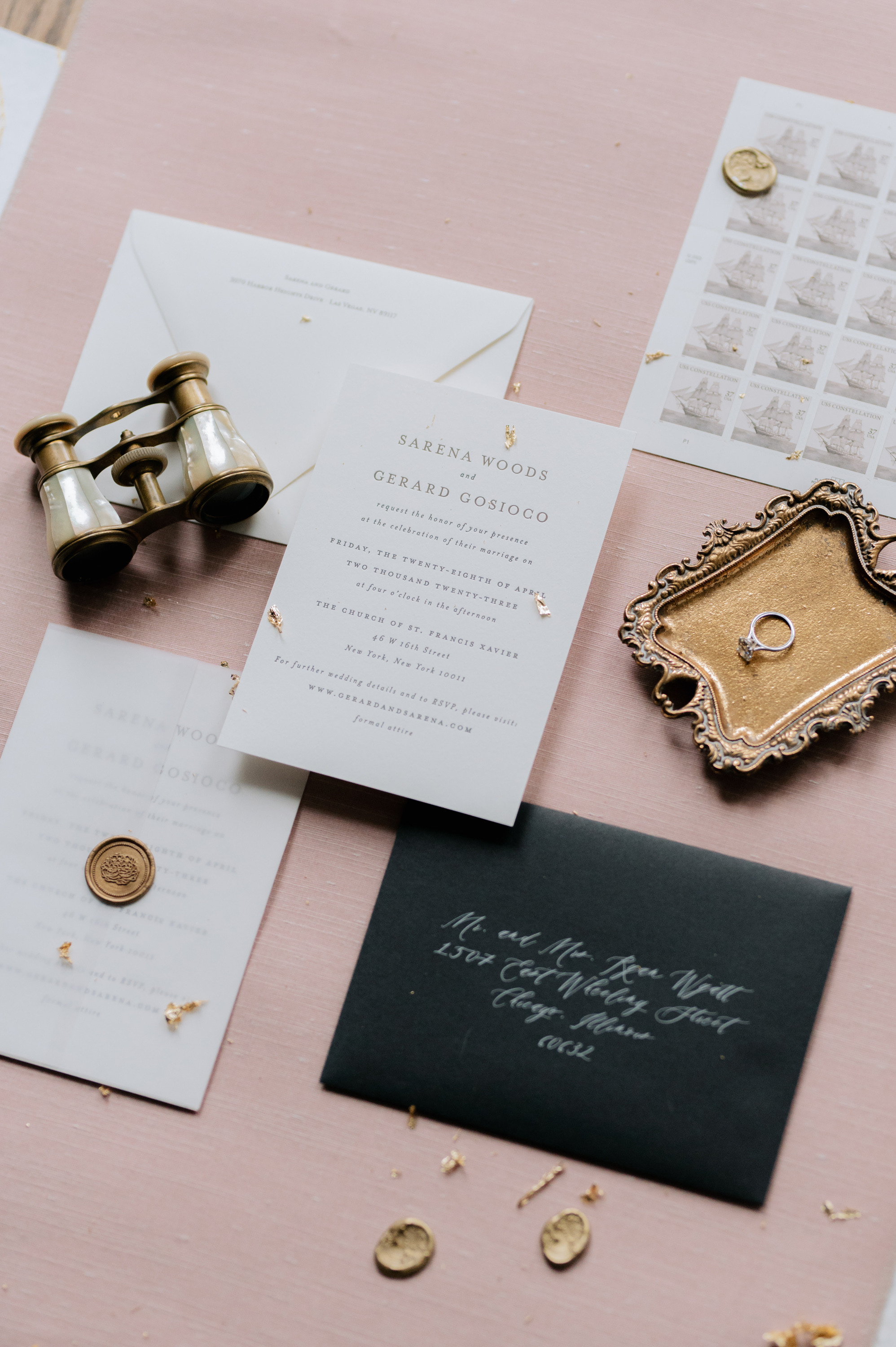 a table with a pink table cloth and a gold and black invitation