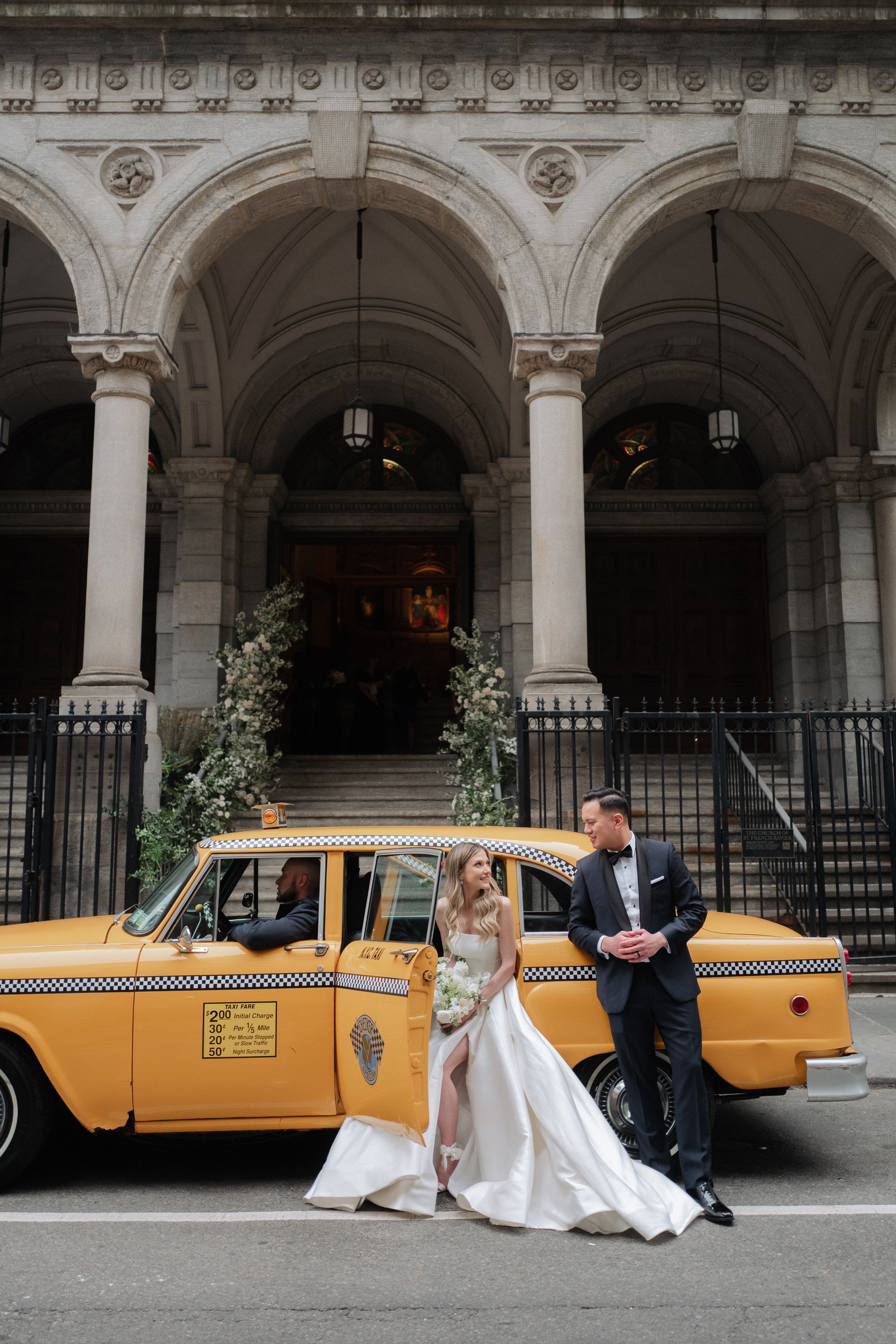 a bride and groom sitting in front of a taxi