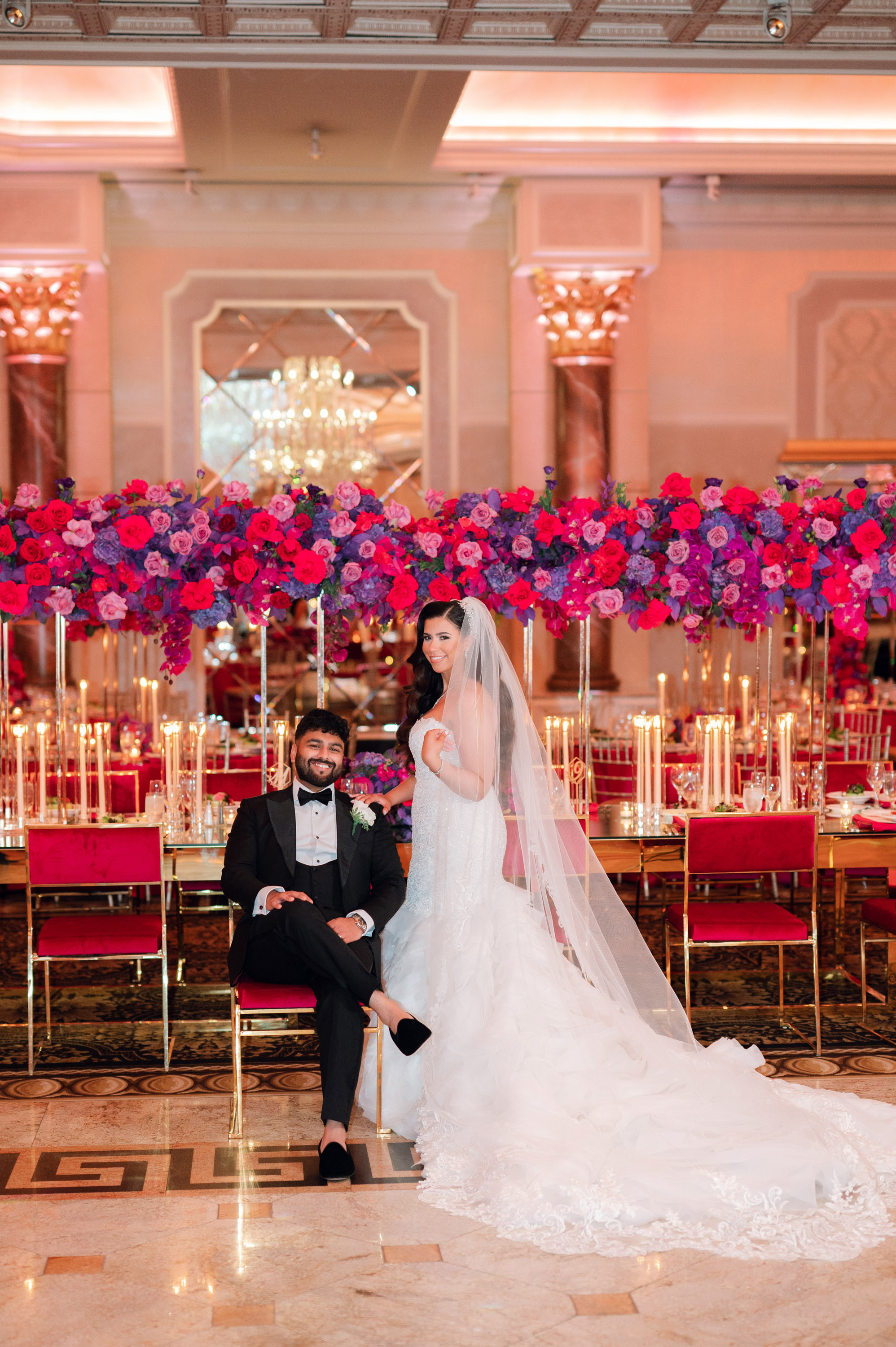 a bride and groom sitting in front of a large floral arrangement