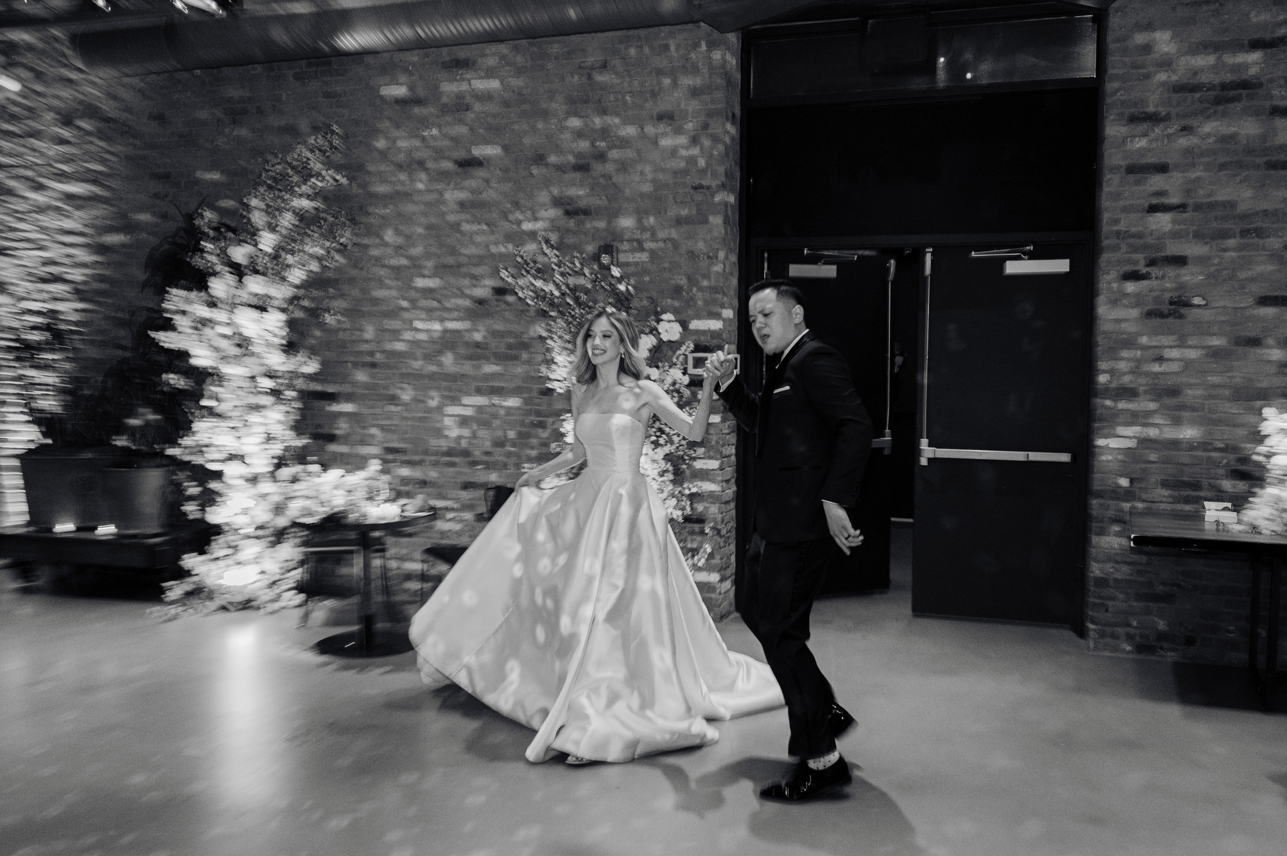 a bride and groom walking through a brick wall