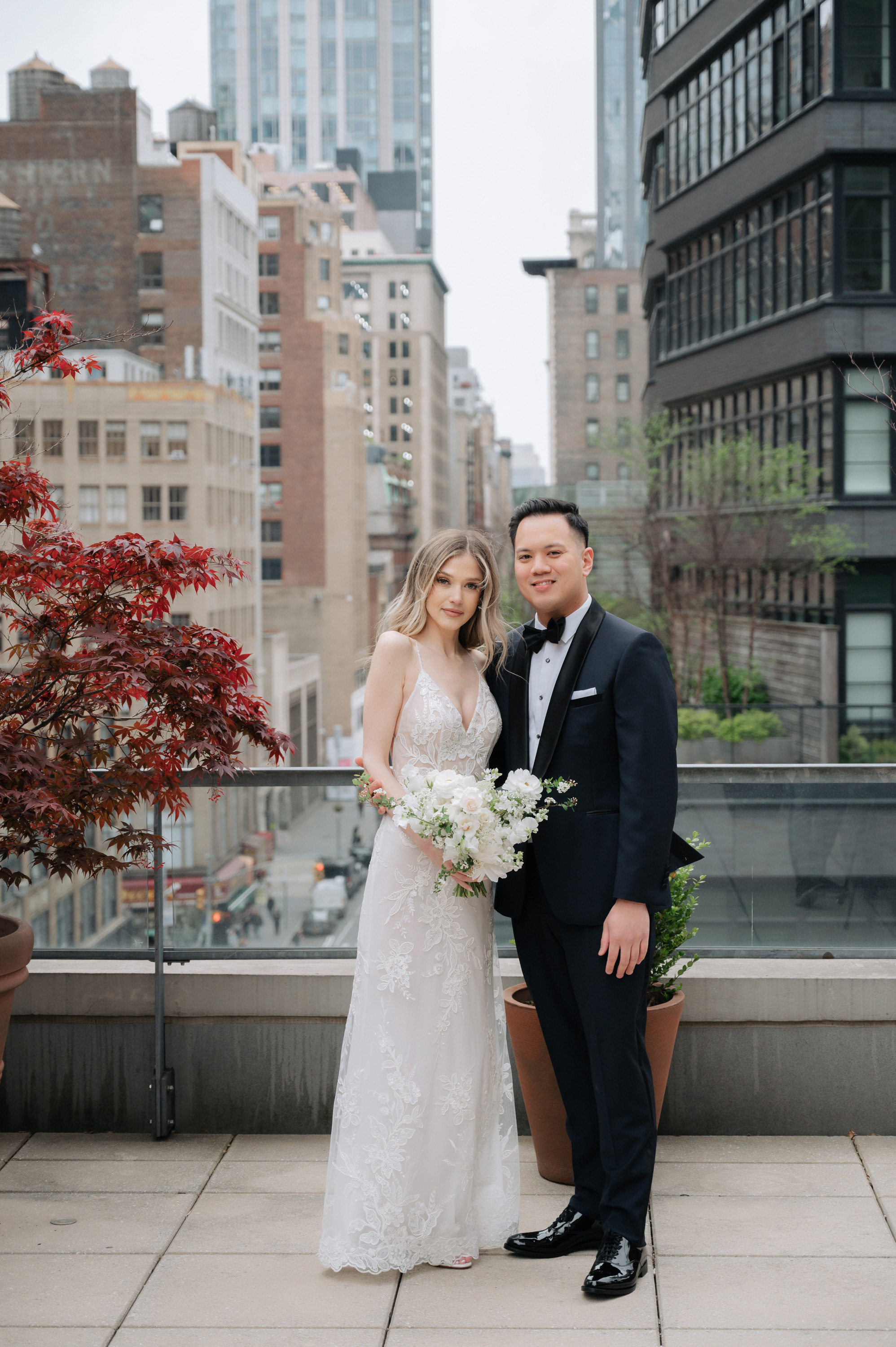 a bride and groom pose for a photo on a rooftop