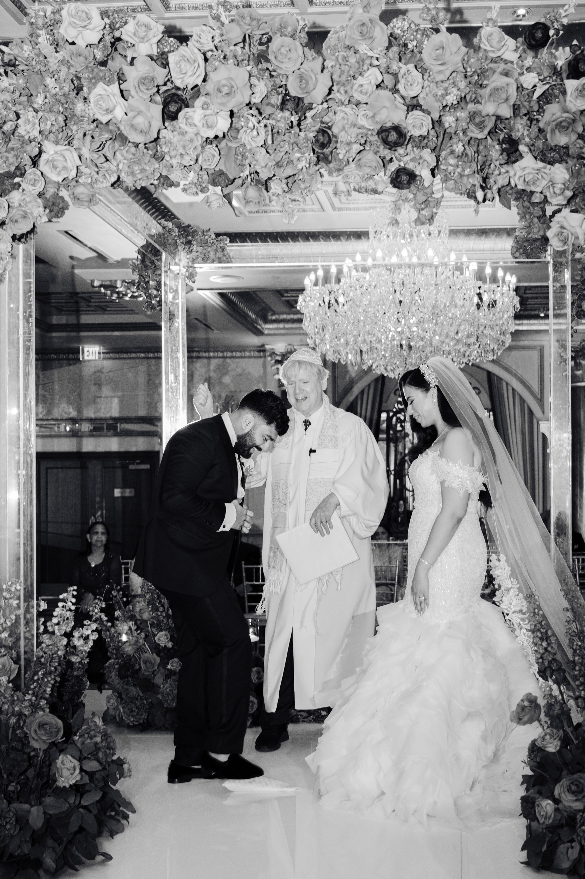 a bride and groom kiss in front of a floral arch