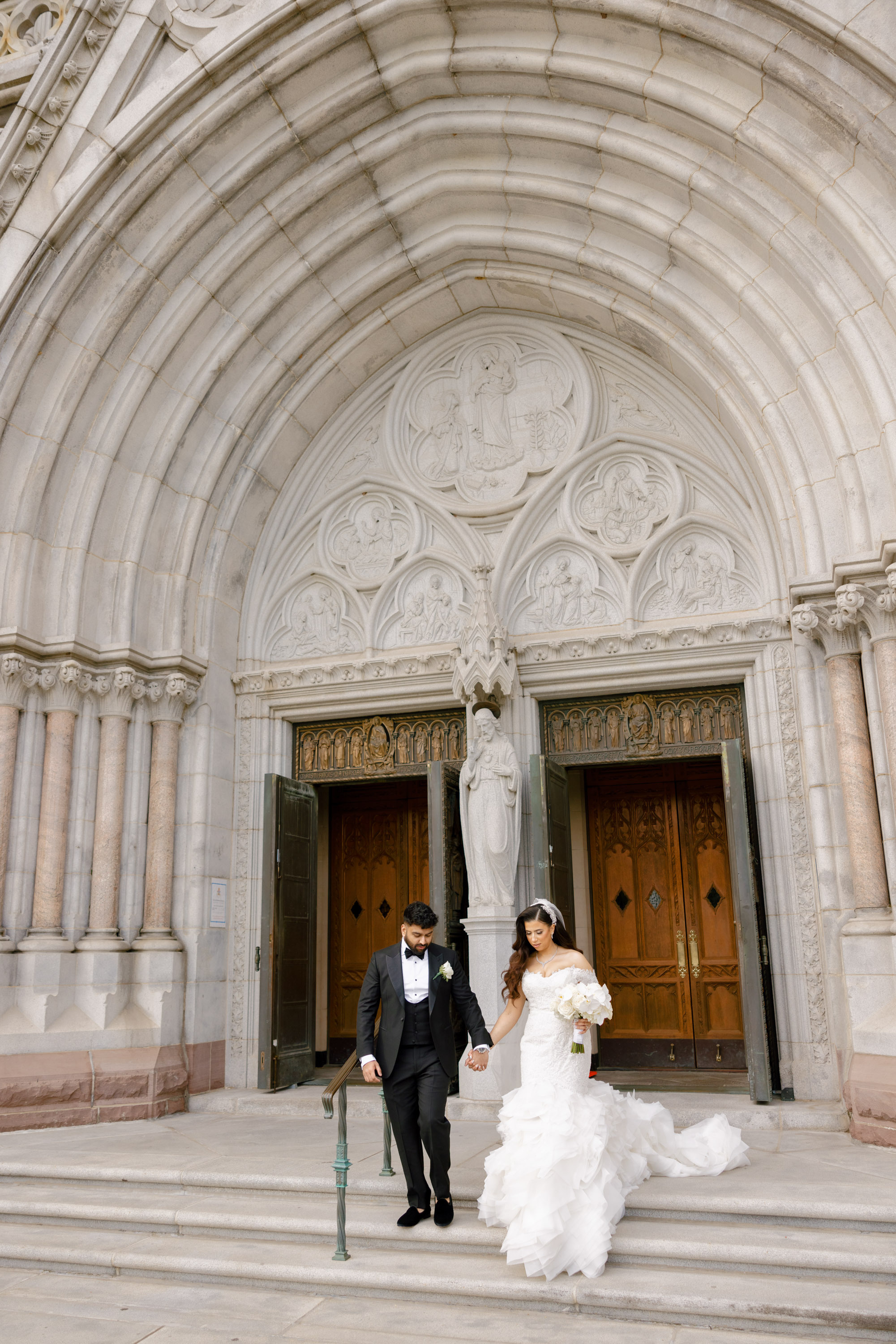 a bride and groom walking down the steps of a church
