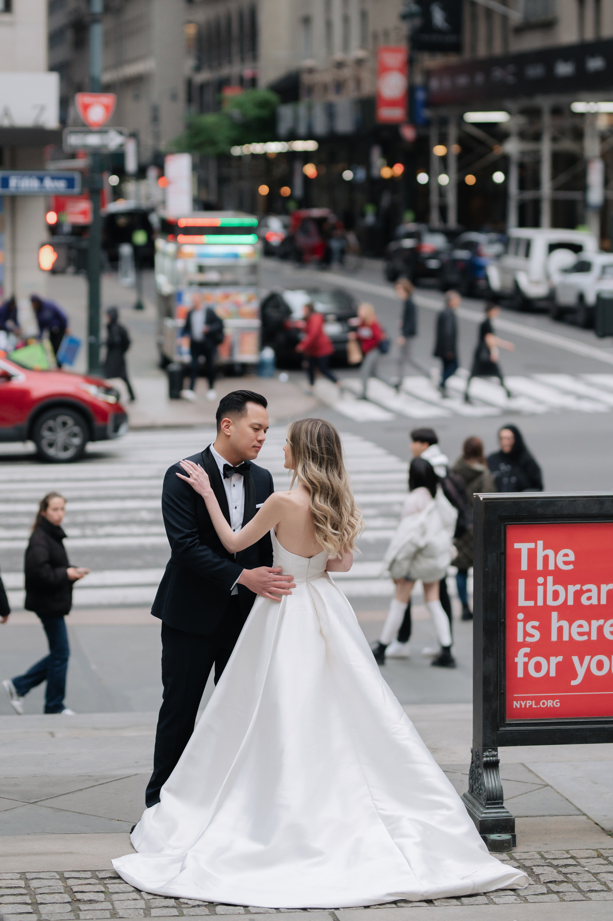 a bride and groom pose for a photo in front of a library for you sign