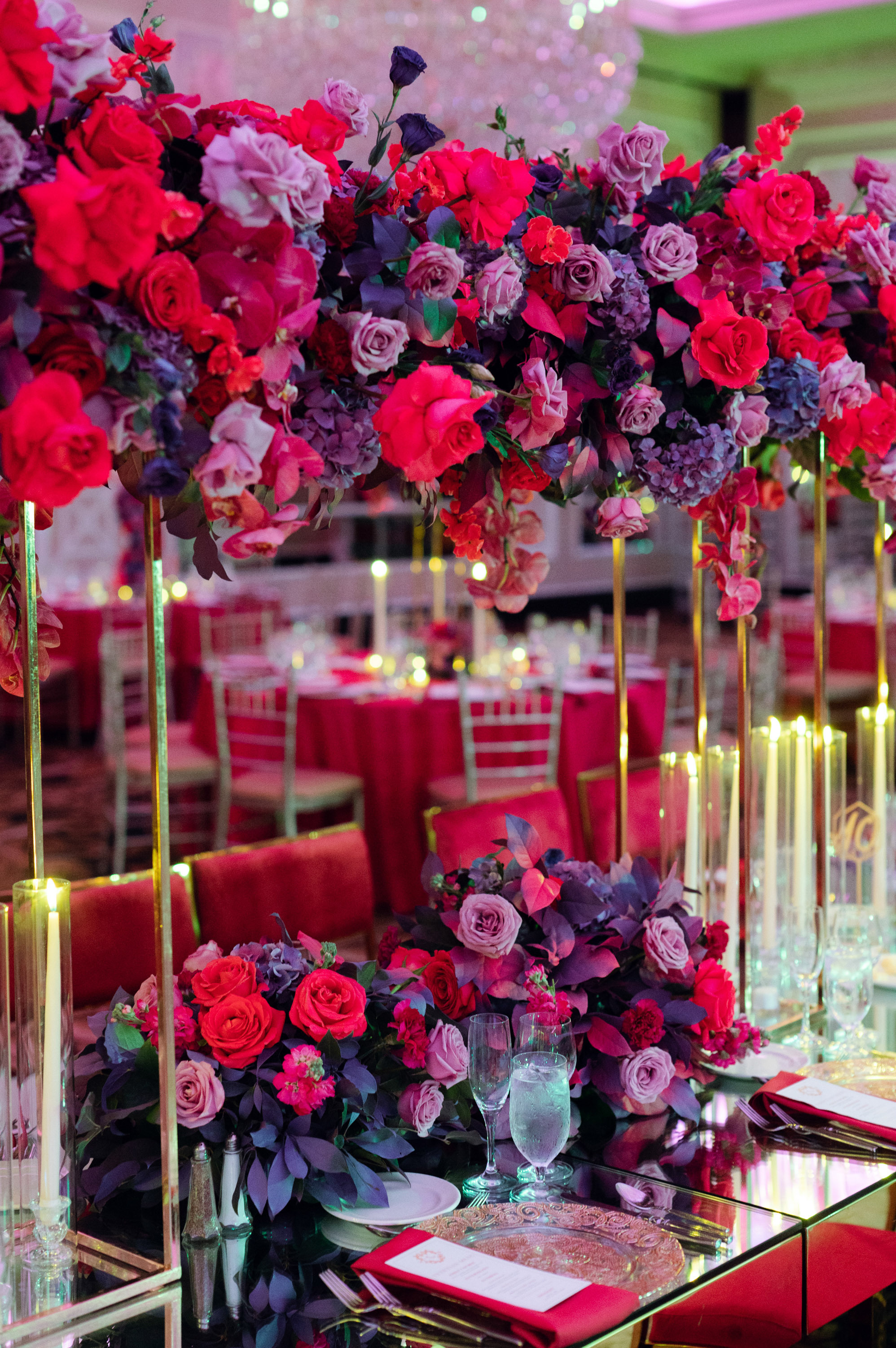 a table with red and purple flowers and candles