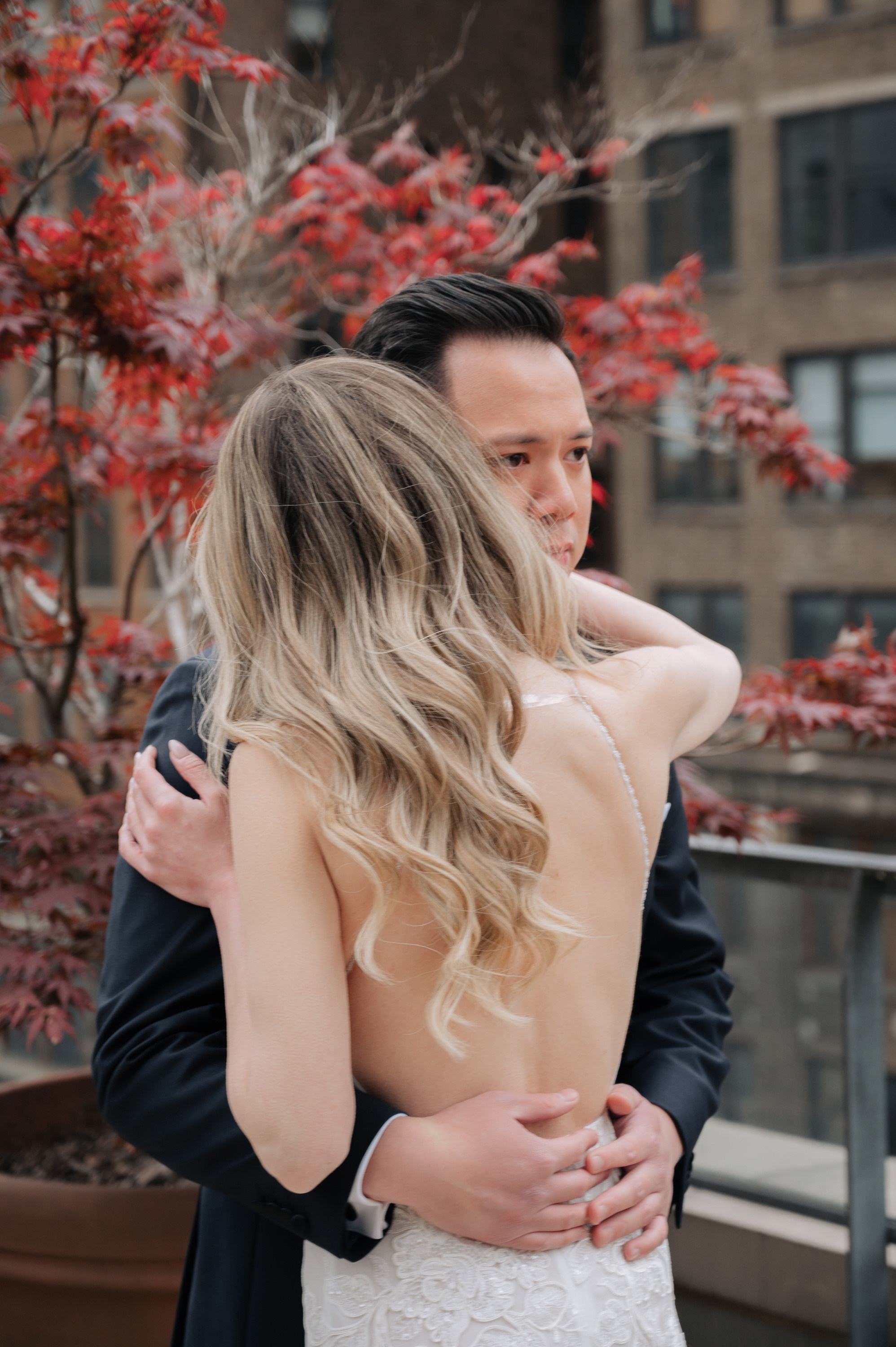 a bride and groom hugging in front of a tree