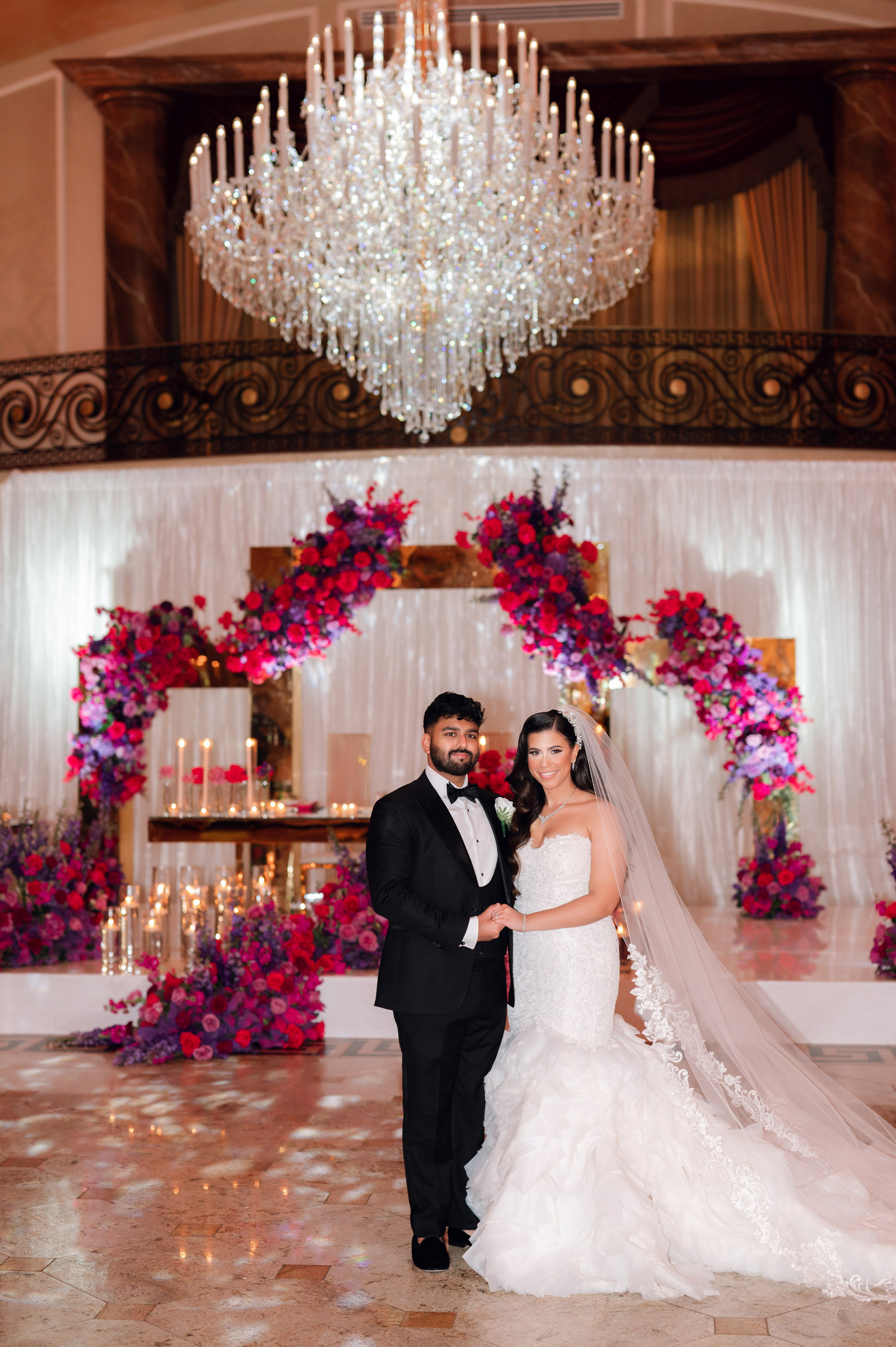a bride and groom pose for a photo in front of a chandel