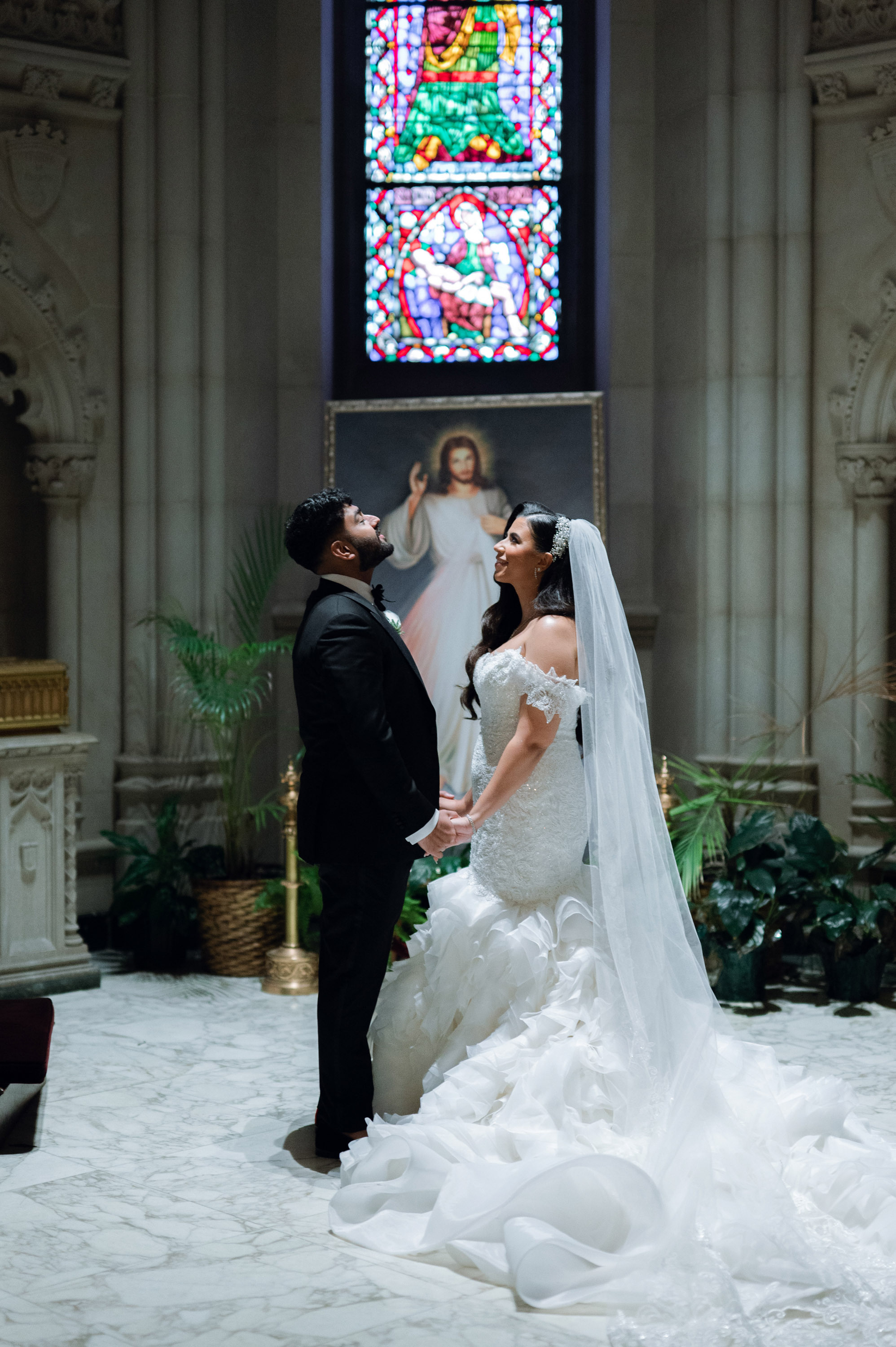 a bride and groom are standing in front of a stained window