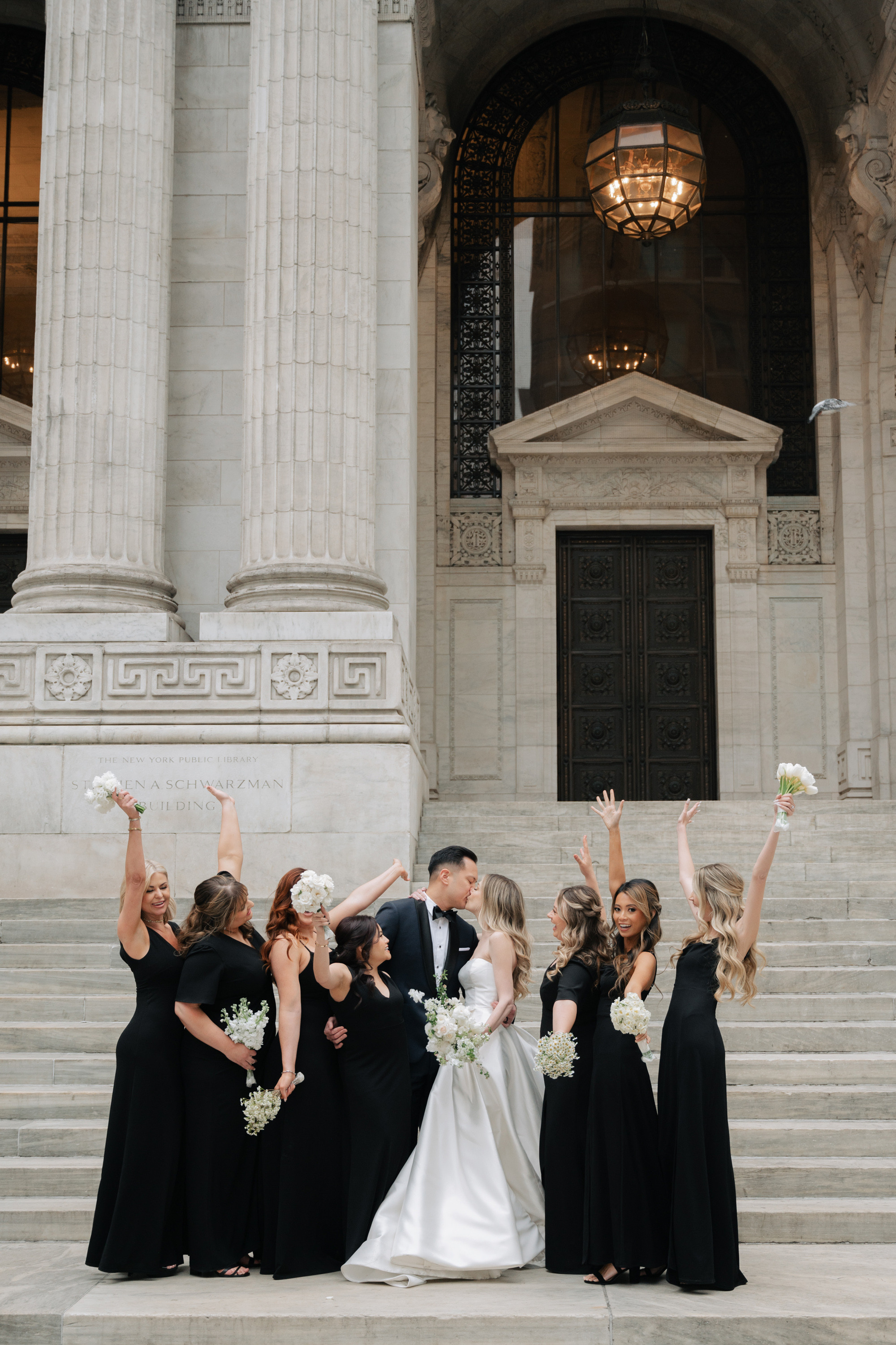 a bride and her bridesmaids pose on the steps of the courthouse