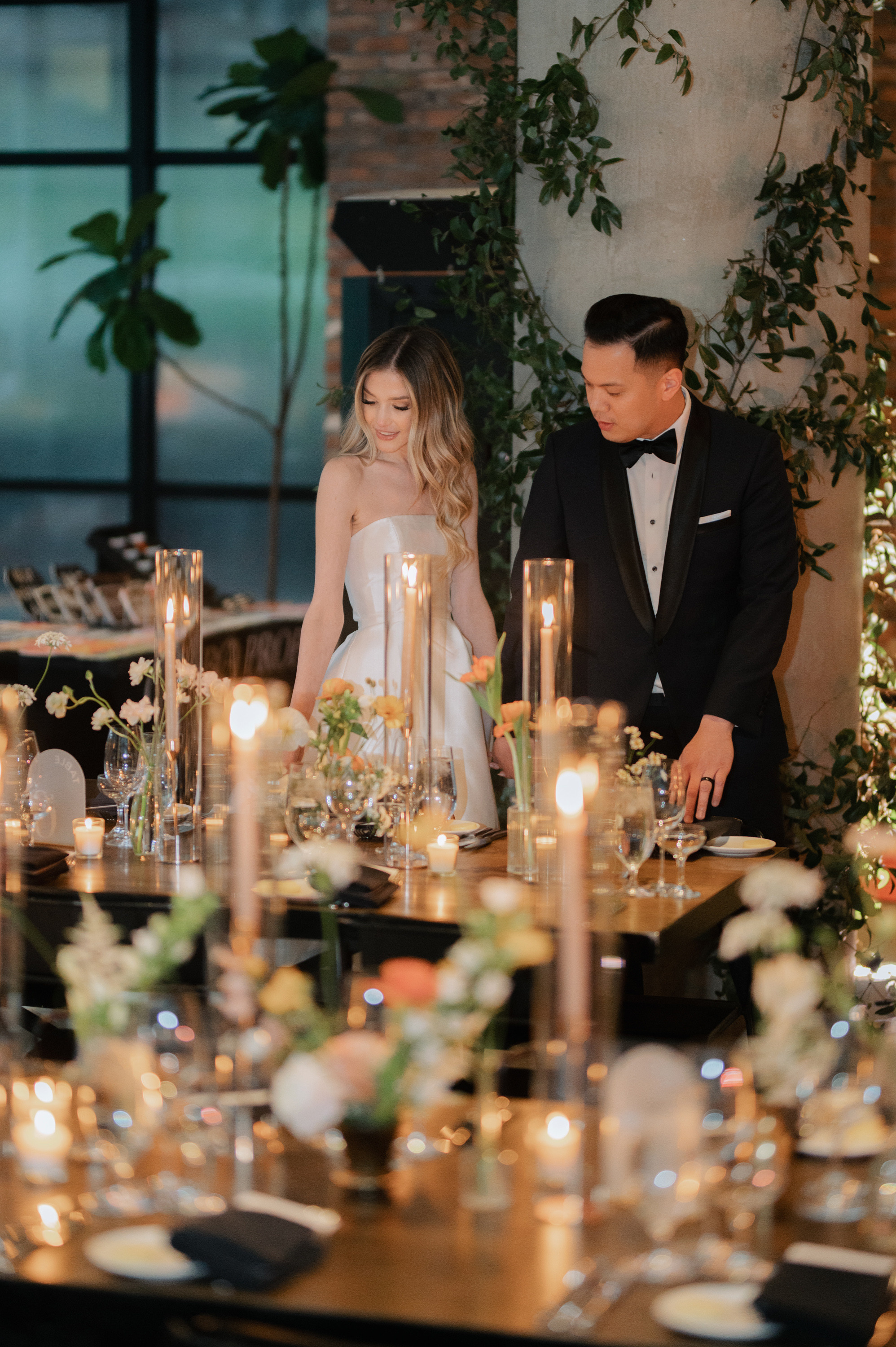 a bride and groom are sitting at a table with candles