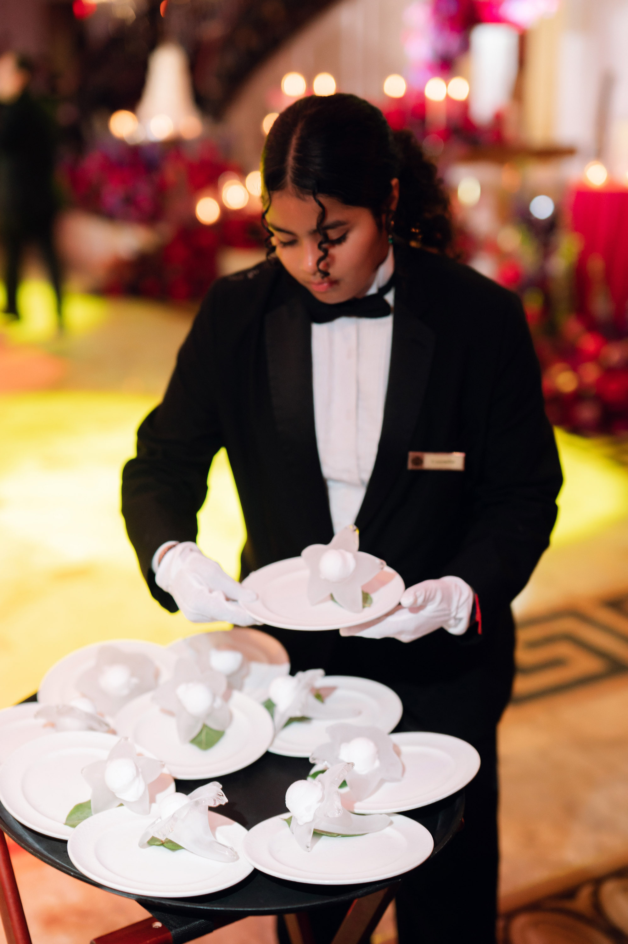 a woman in a tuxed suit holding a plate with a bunch of flowers