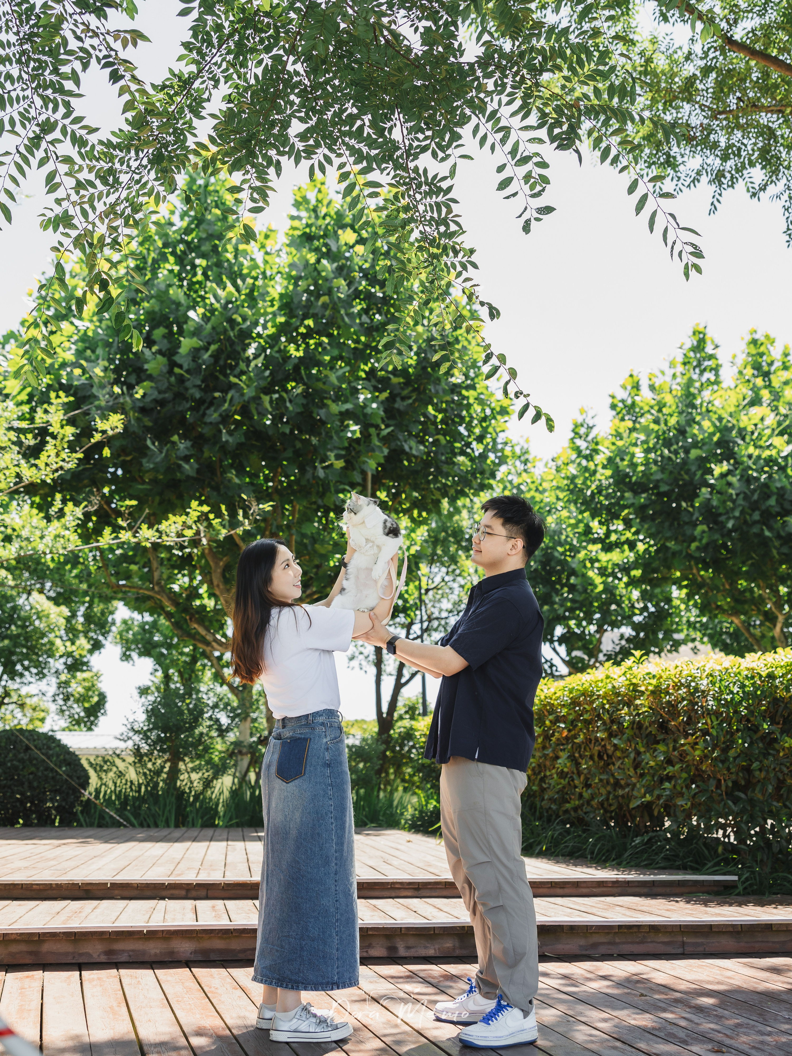 Couple lifting their cat together, joyful family moment outdoor