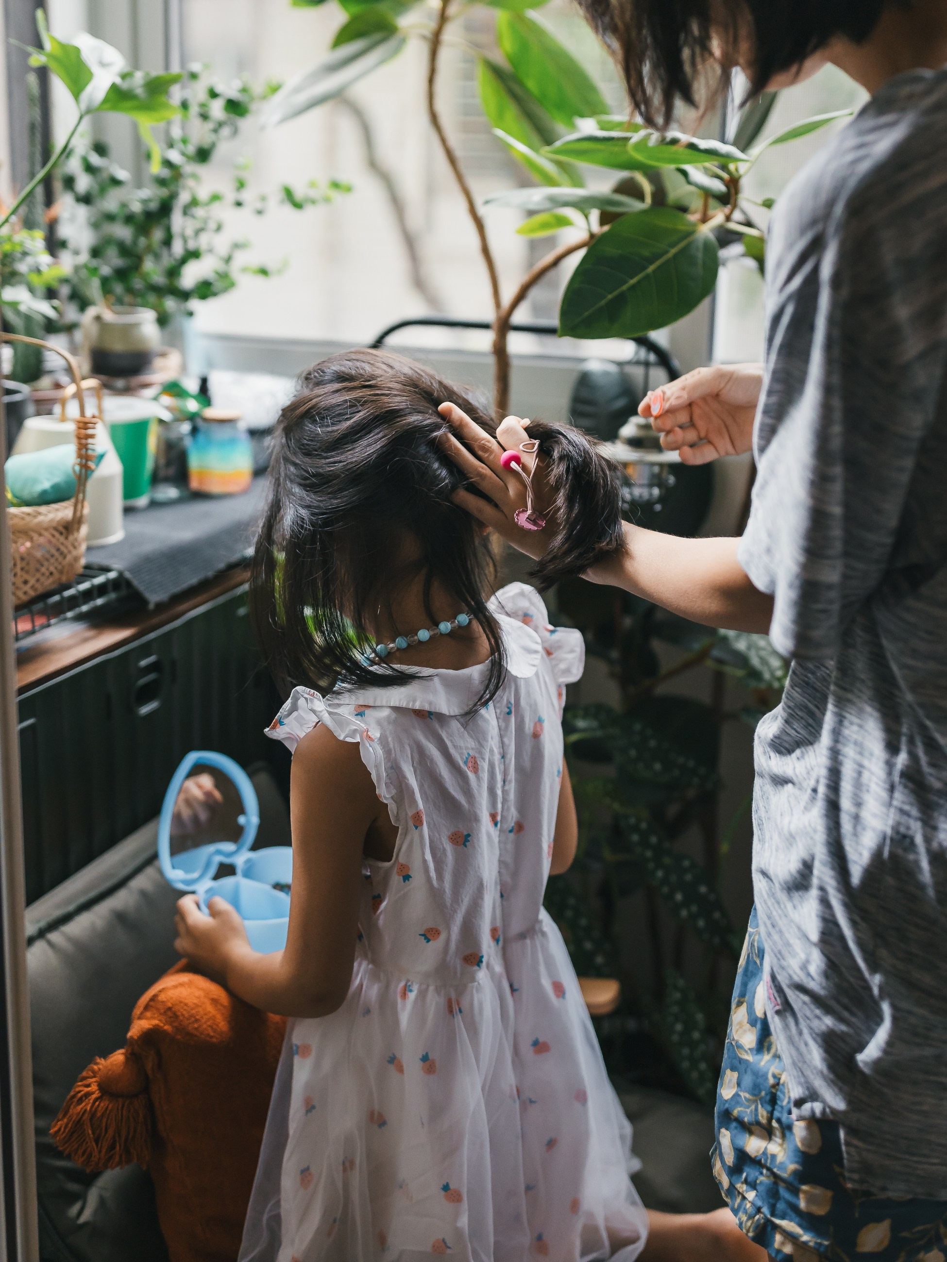 The mother is braiding her daughter's hair.