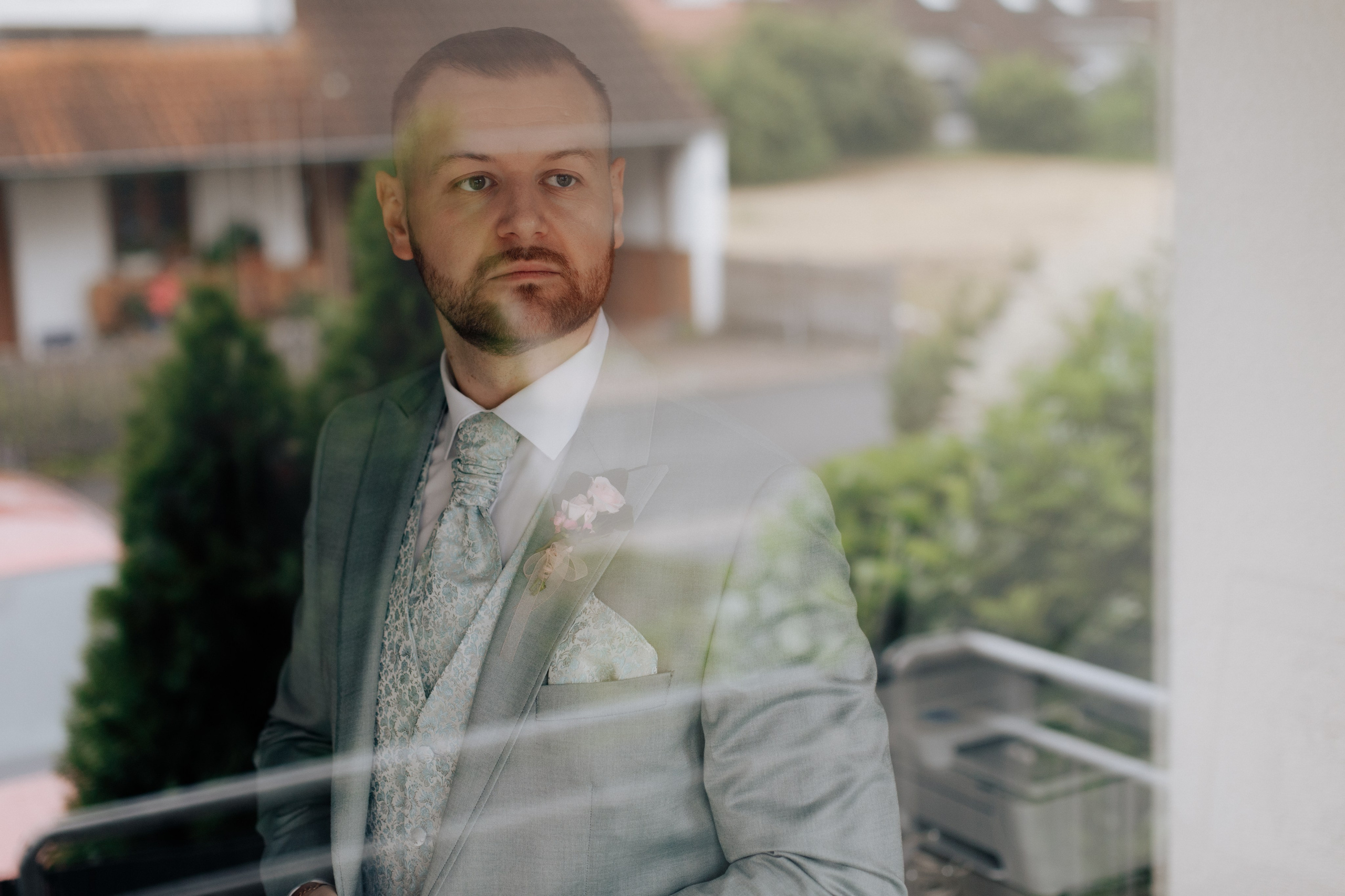 Der Bräutigam schaut nachdenklich aus dem Fenster, voller Vorfreude und Aufregung. 