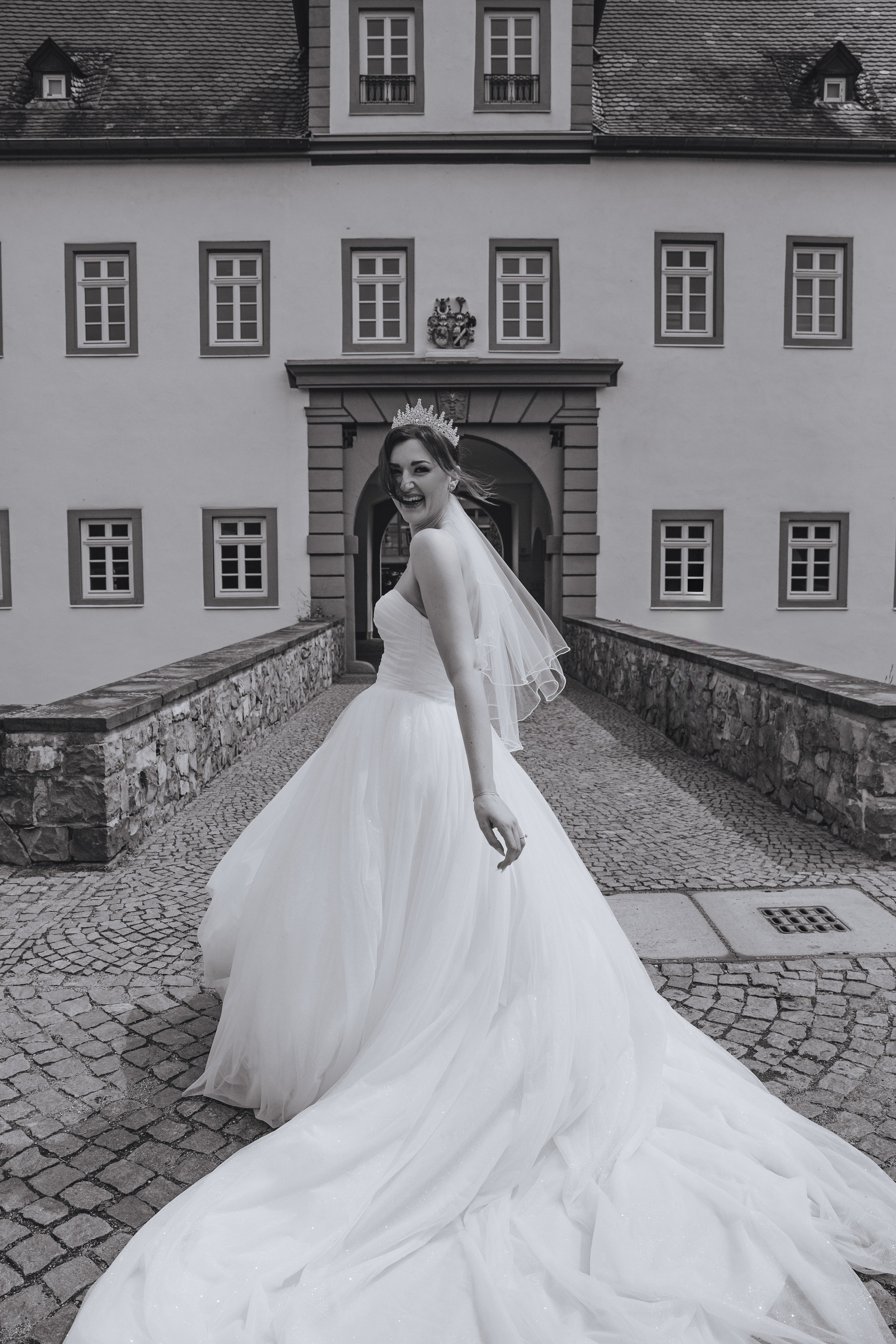 Schwarz-Weiß-Foto, auf dem die Braut sich zu uns dreht und lacht.