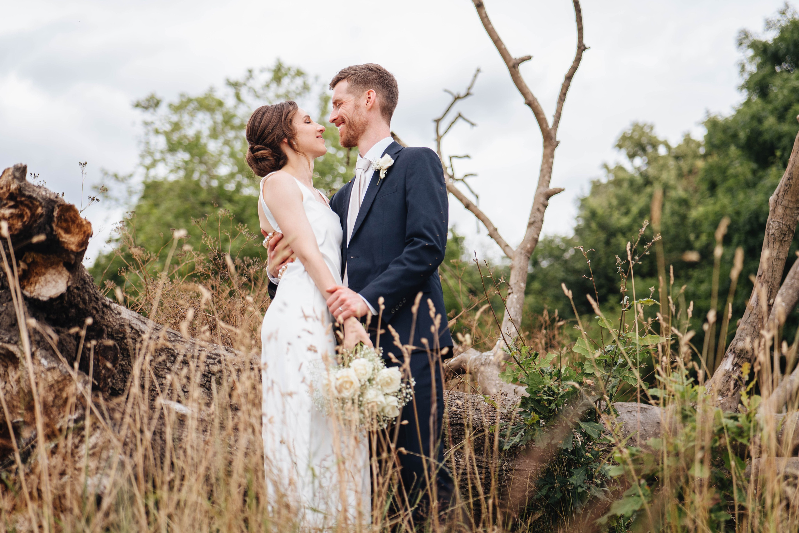bride and groom posing near an old dead tree
