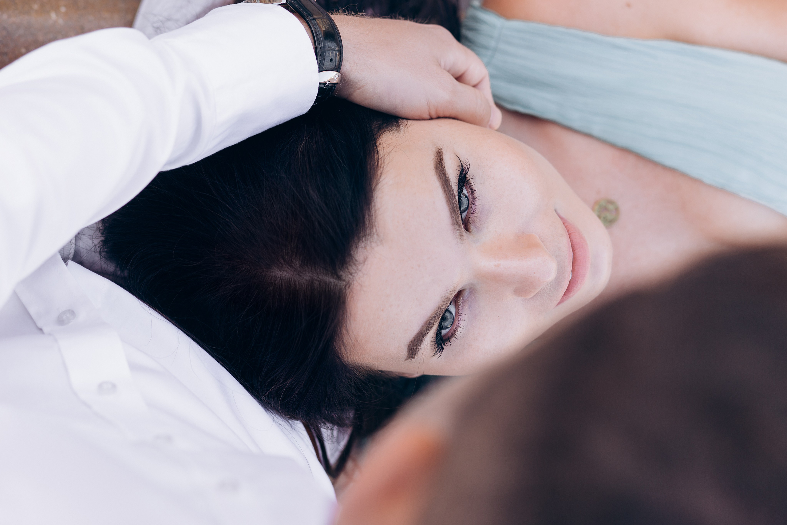 Romantic close-up portrait of a woman lying in her partner’s lap, gazing up with a soft smile while his hand gently rests on her head, capturing an intimate moment of love and connection Valencia, Spain.