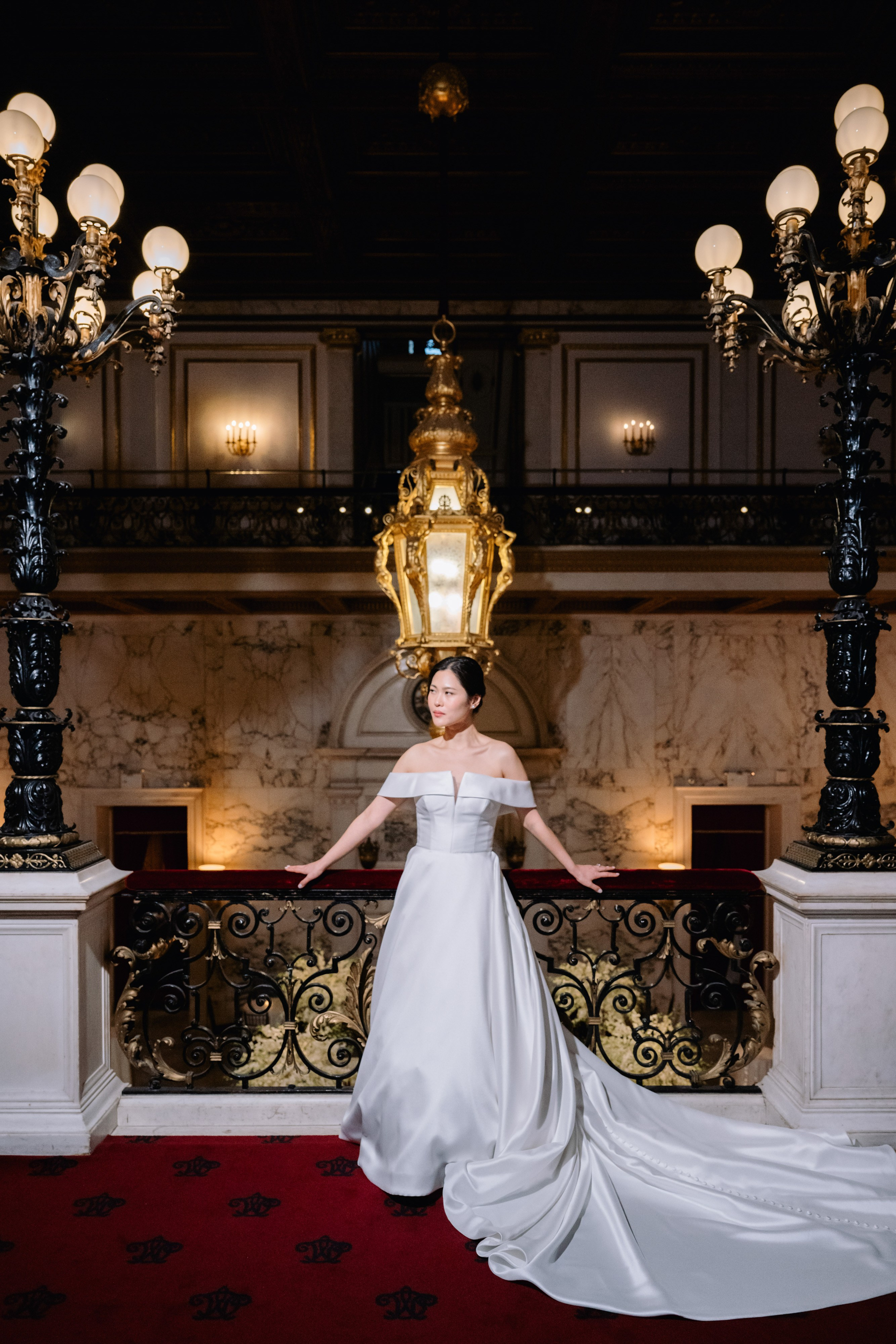 a woman in a white dress standing in front of a chandel