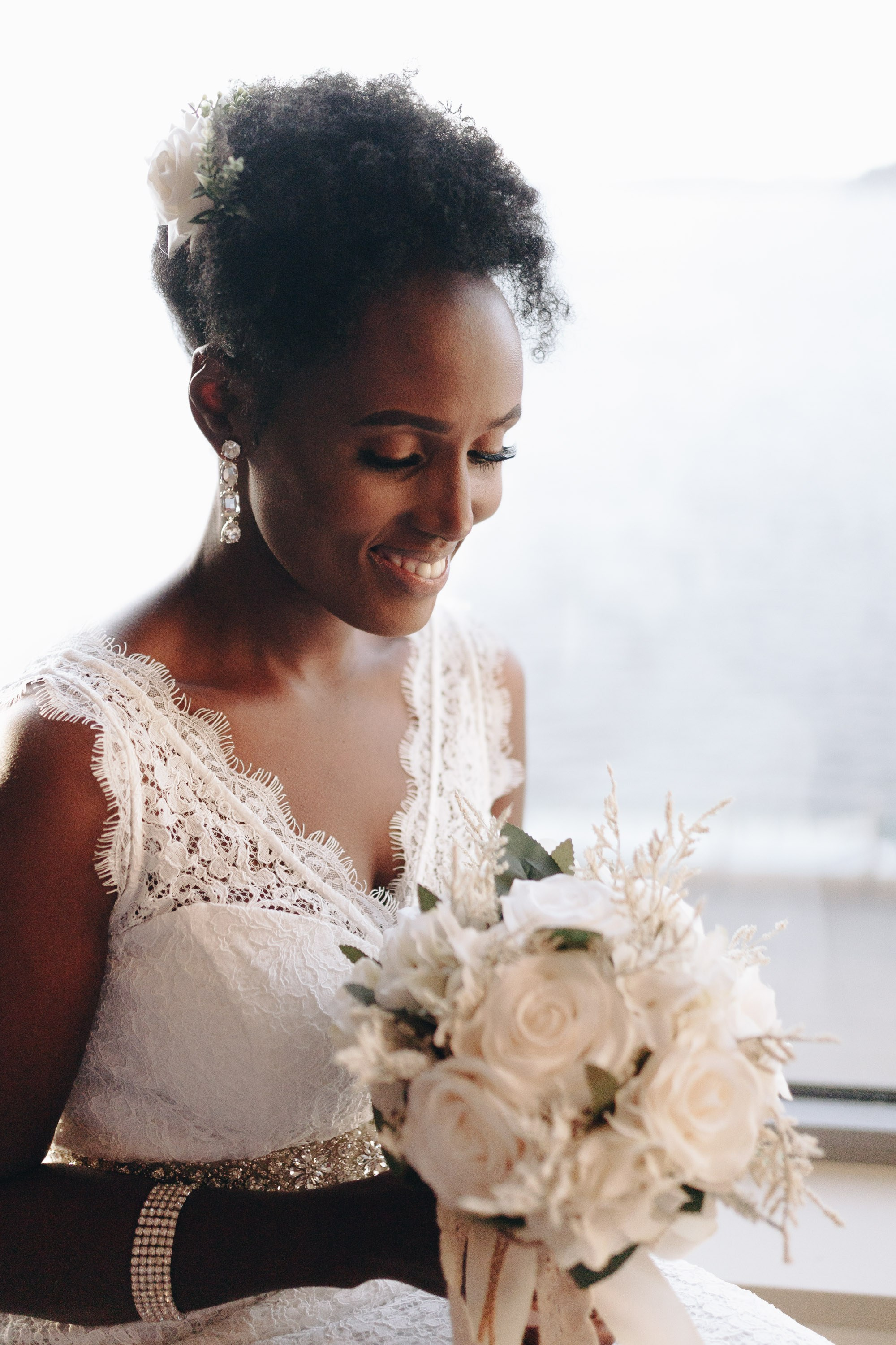 Bride in white dress holding bouquet, looking down