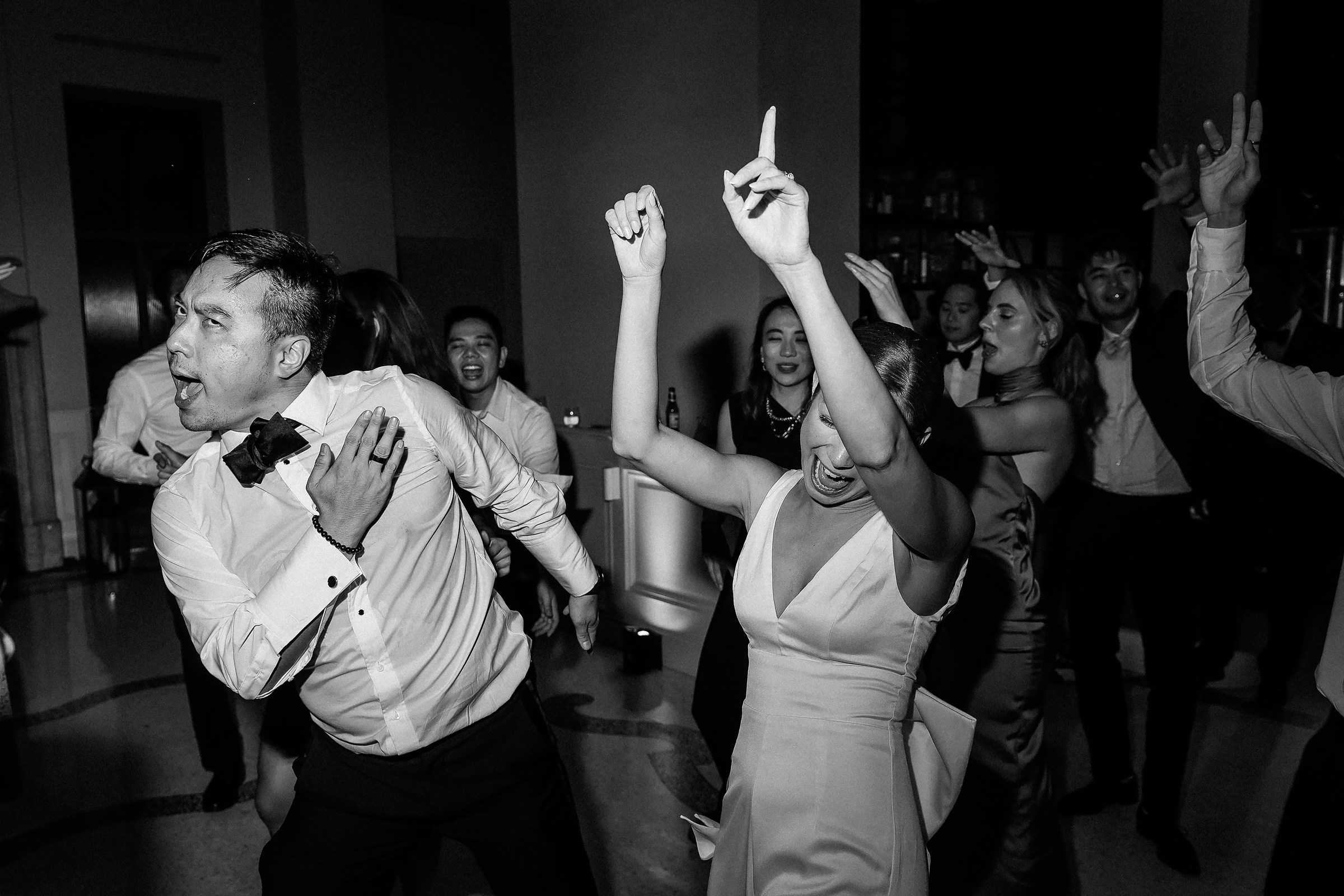 A bride and groom share a joyful dance together at their wedding reception, surrounded by love and celebration