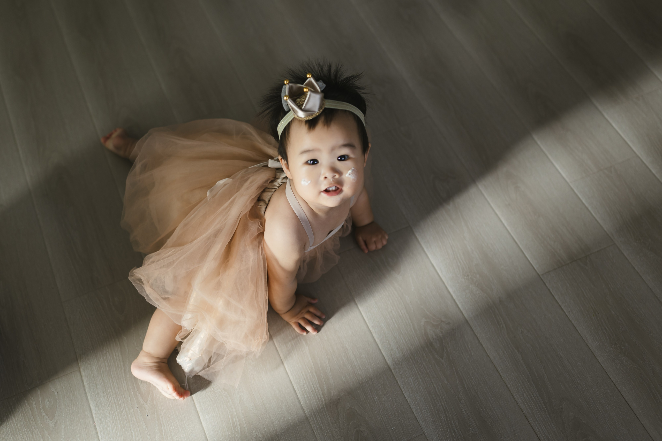 The baby is one year old, and her mother has placed a "crown" on her head.