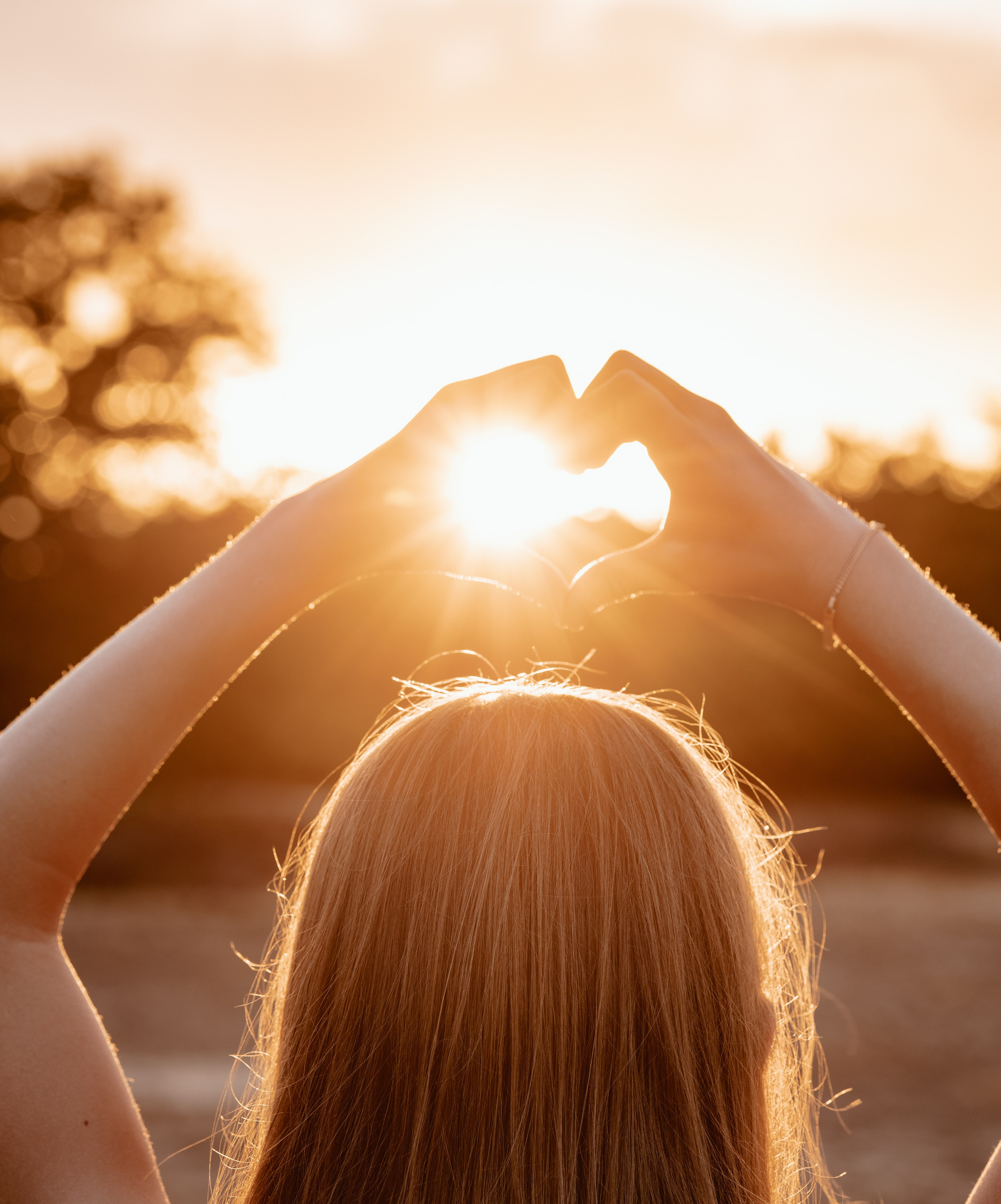 Meisje vormt een hart met haar handen in de zon tijdens familieshoot door Kapture Fotografie