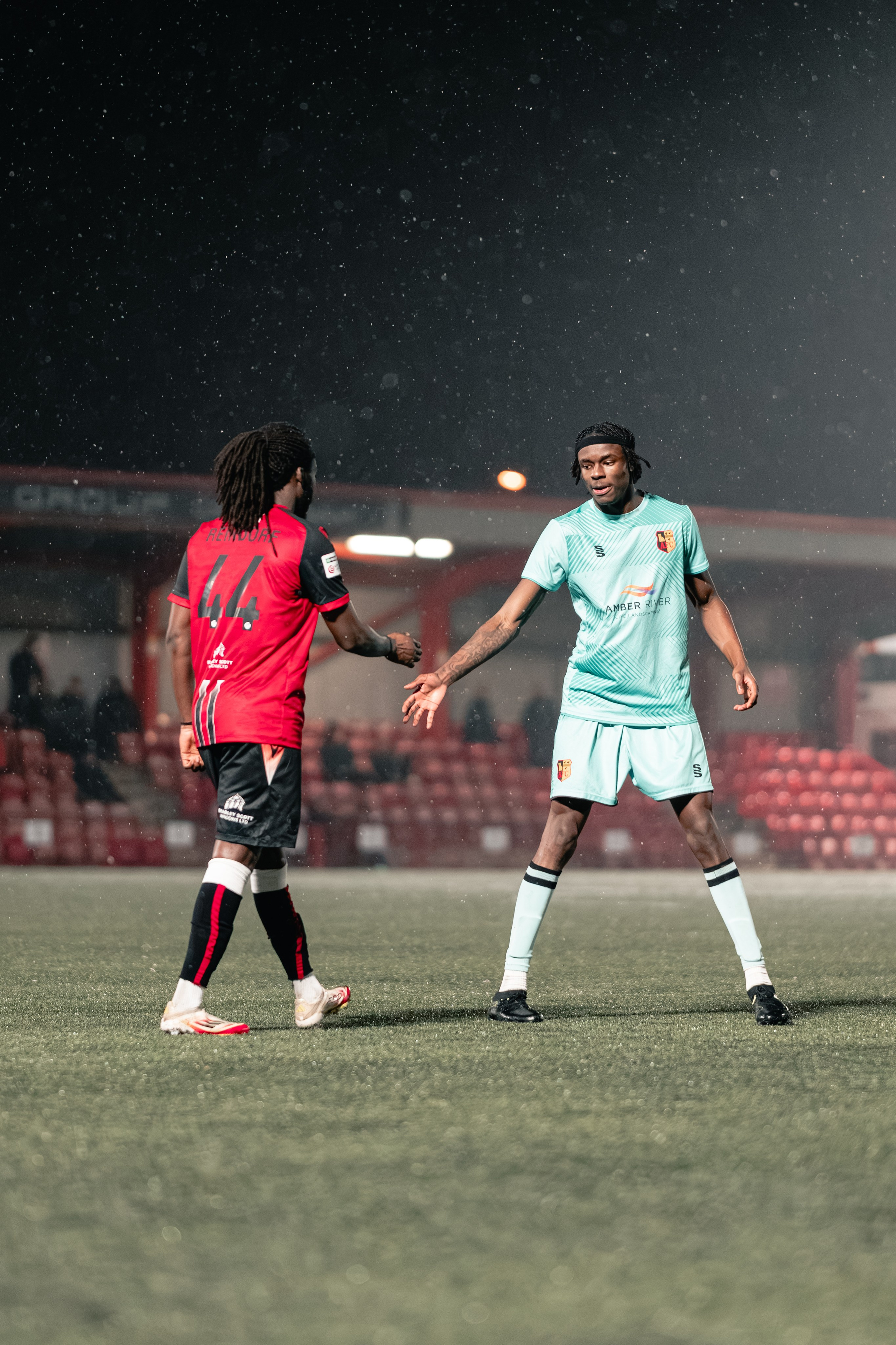 Michael Reindorf of Tamworth FC faces Nile Timson of Alvechurch in falling rain under the floodlights during the Birmingham Senior Cup match at The Lamb Ground, Feb 3 2026.