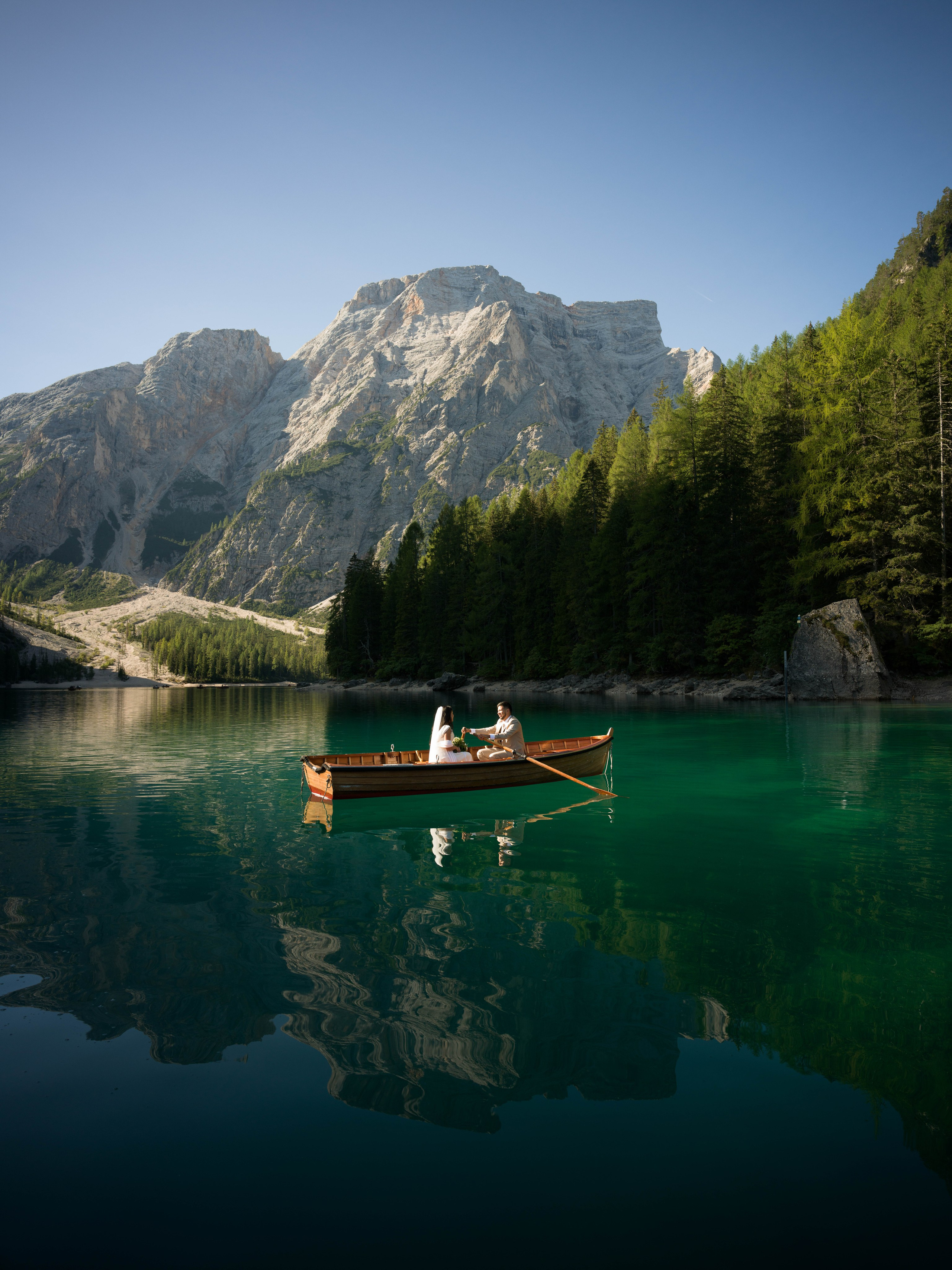 Lake Braies elopement photos and video in the Dolomites featuring a couple on the lake and walking along the shoreline