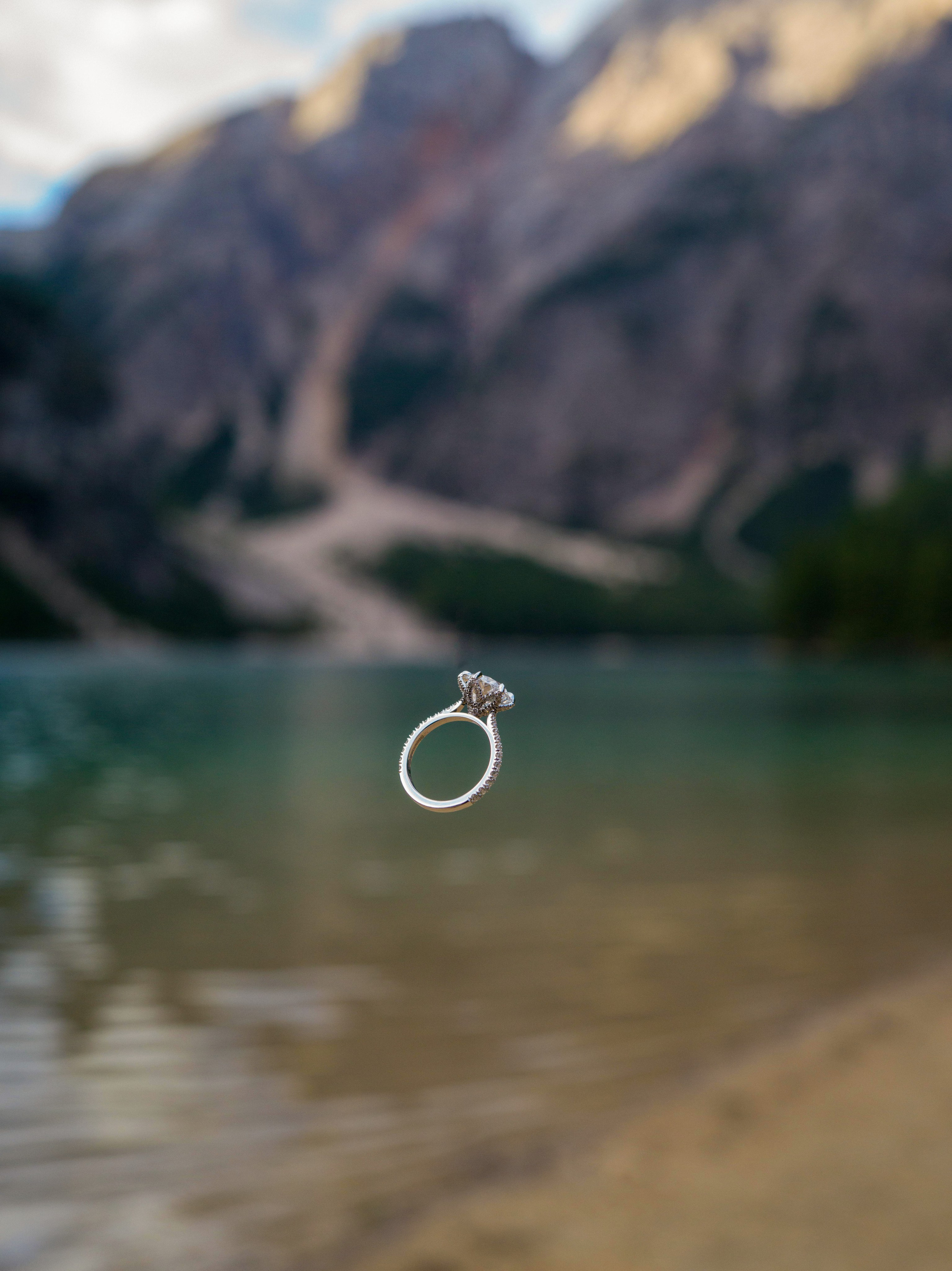 Proposal, Lake Braies, Dolomites, Italy – engagement ring suspended in mid-air over the turquoise lake
