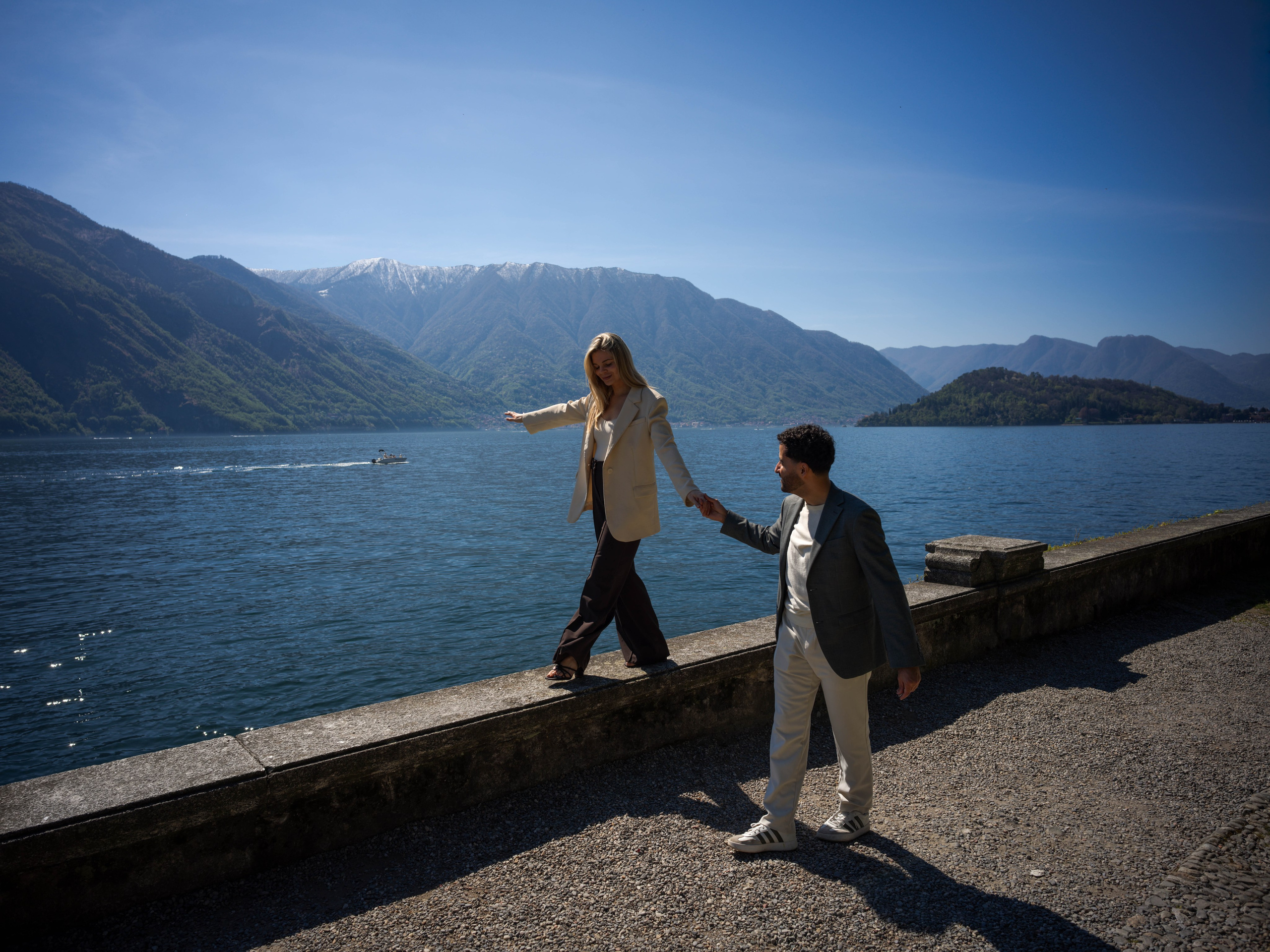 A quiet, tender moment on a park bench right after the proposal, the couple embracing with Lake Como scenery around them.