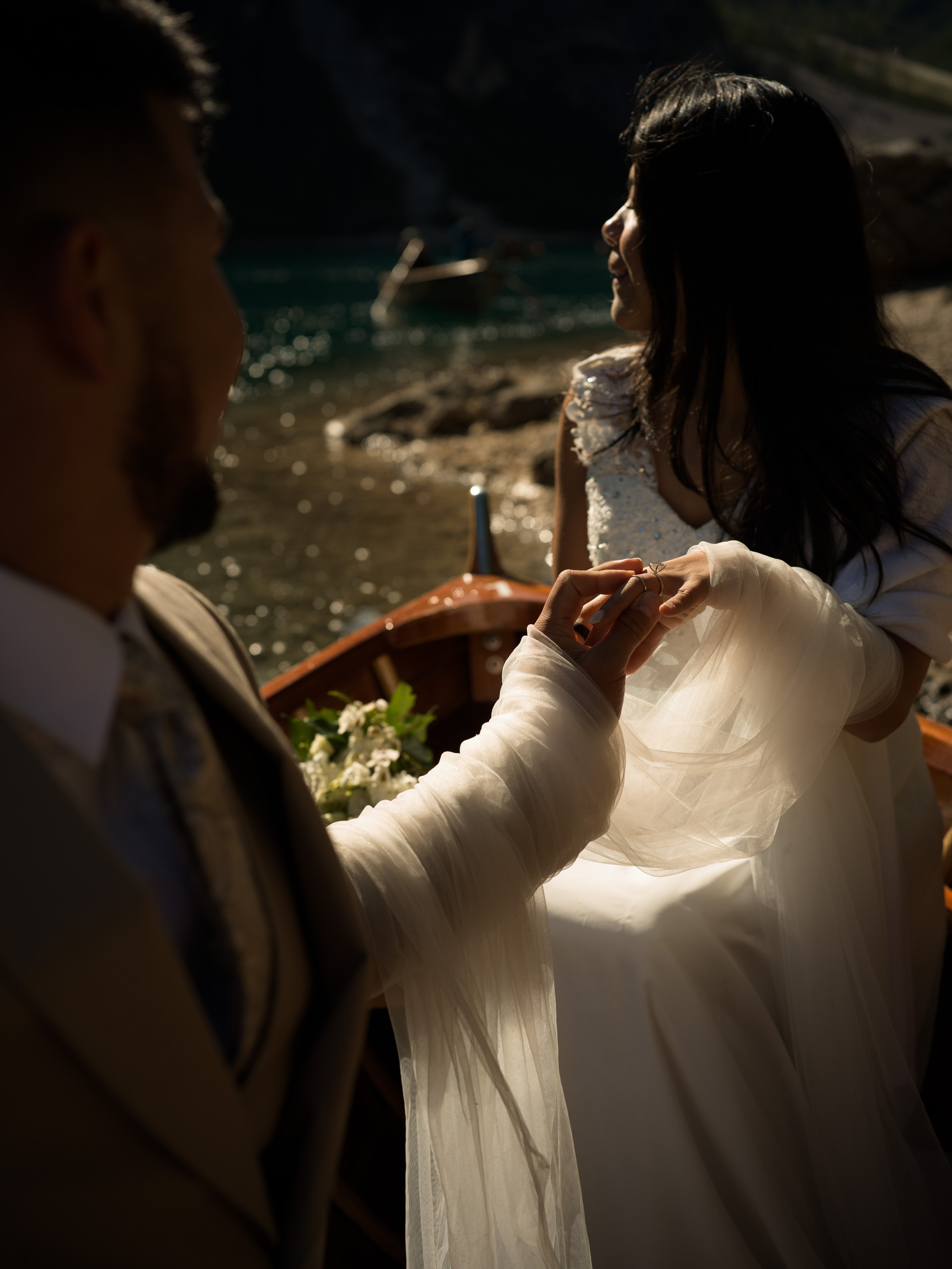 Lake Braies elopement at sunrise, couple in a traditional wooden boat on the turquoise lake in the Dolomites, Italy