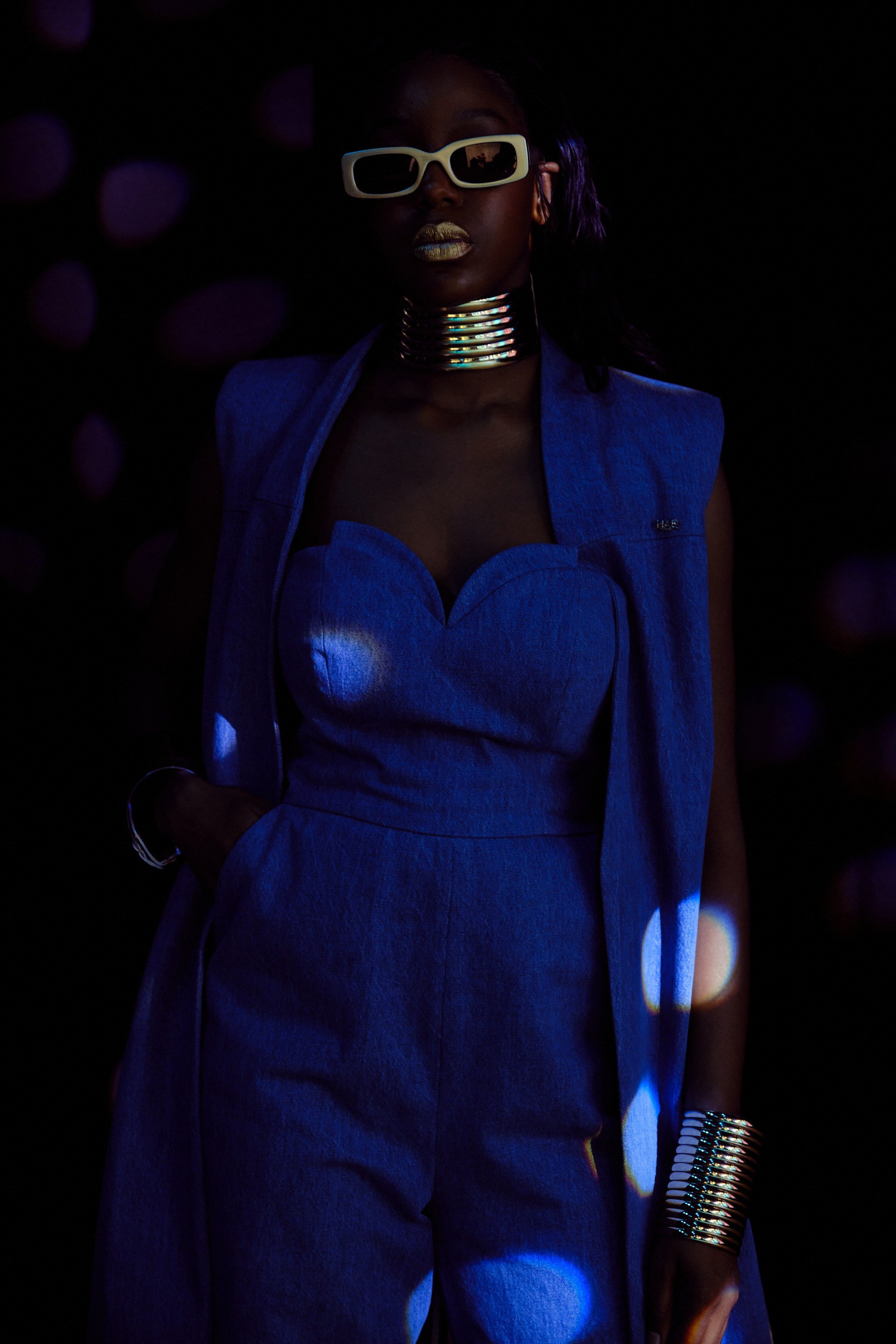 Studio commercial fashion portrait of a vibrant blue jumpsuit under cinematic spotted lighting