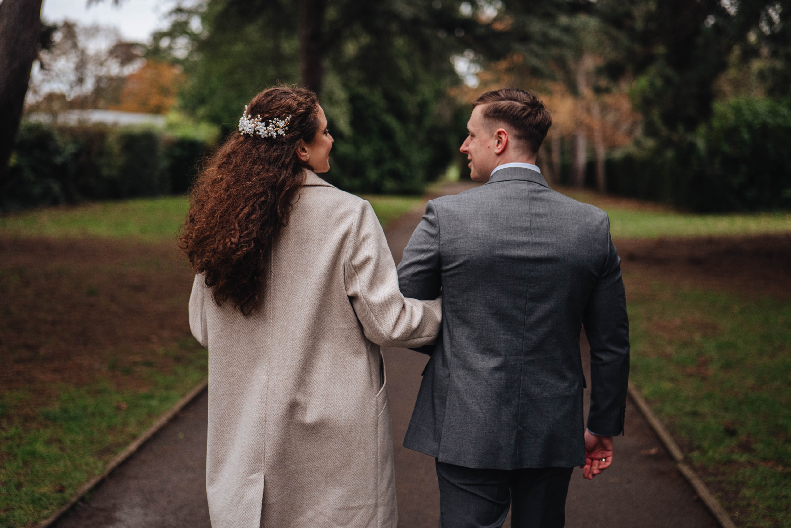 groom and bride from the back walking down the path in the park