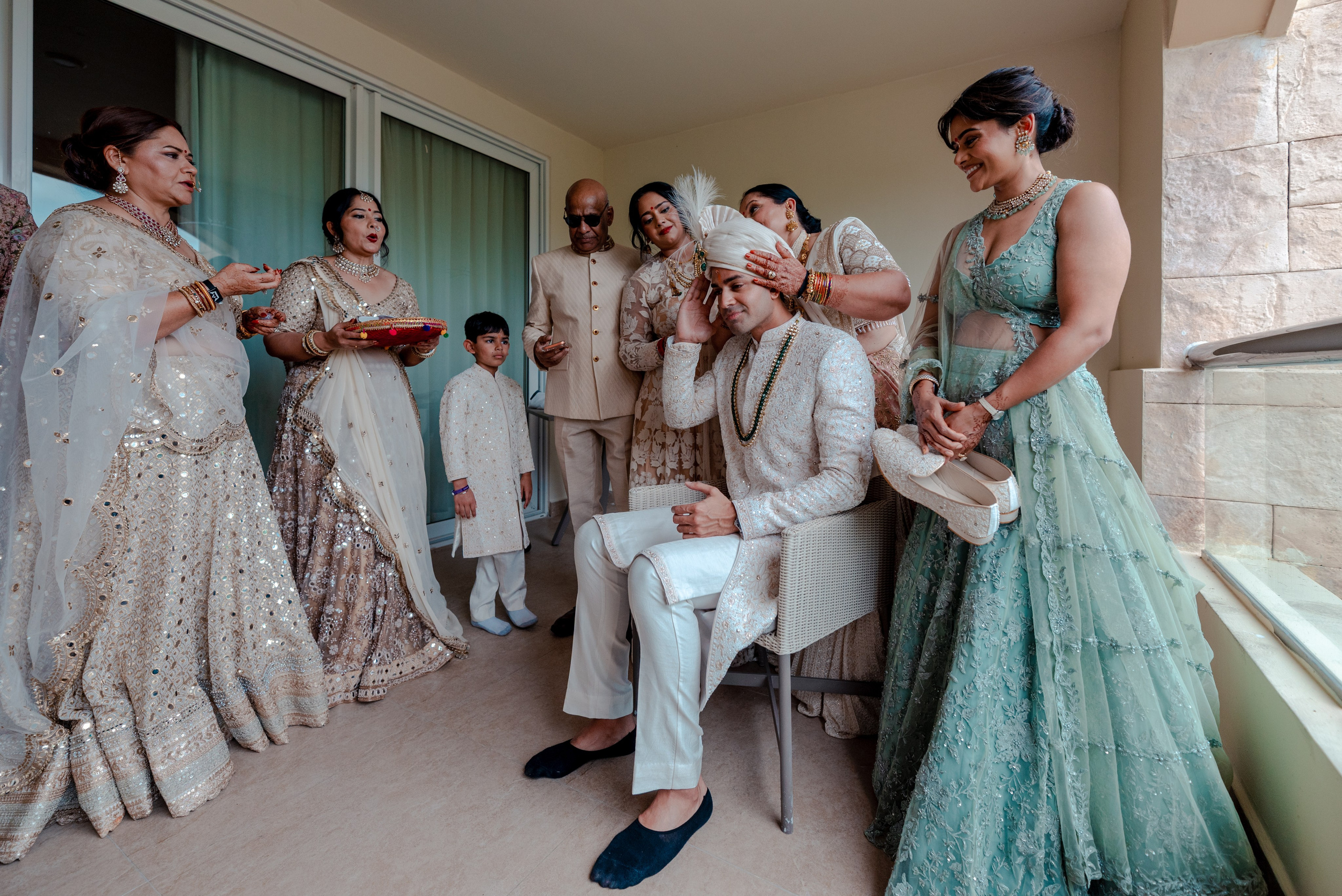 Indian wedding groom surrounded by family while his mother places the turban before the Baraat ceremony in Cancun Mexico
