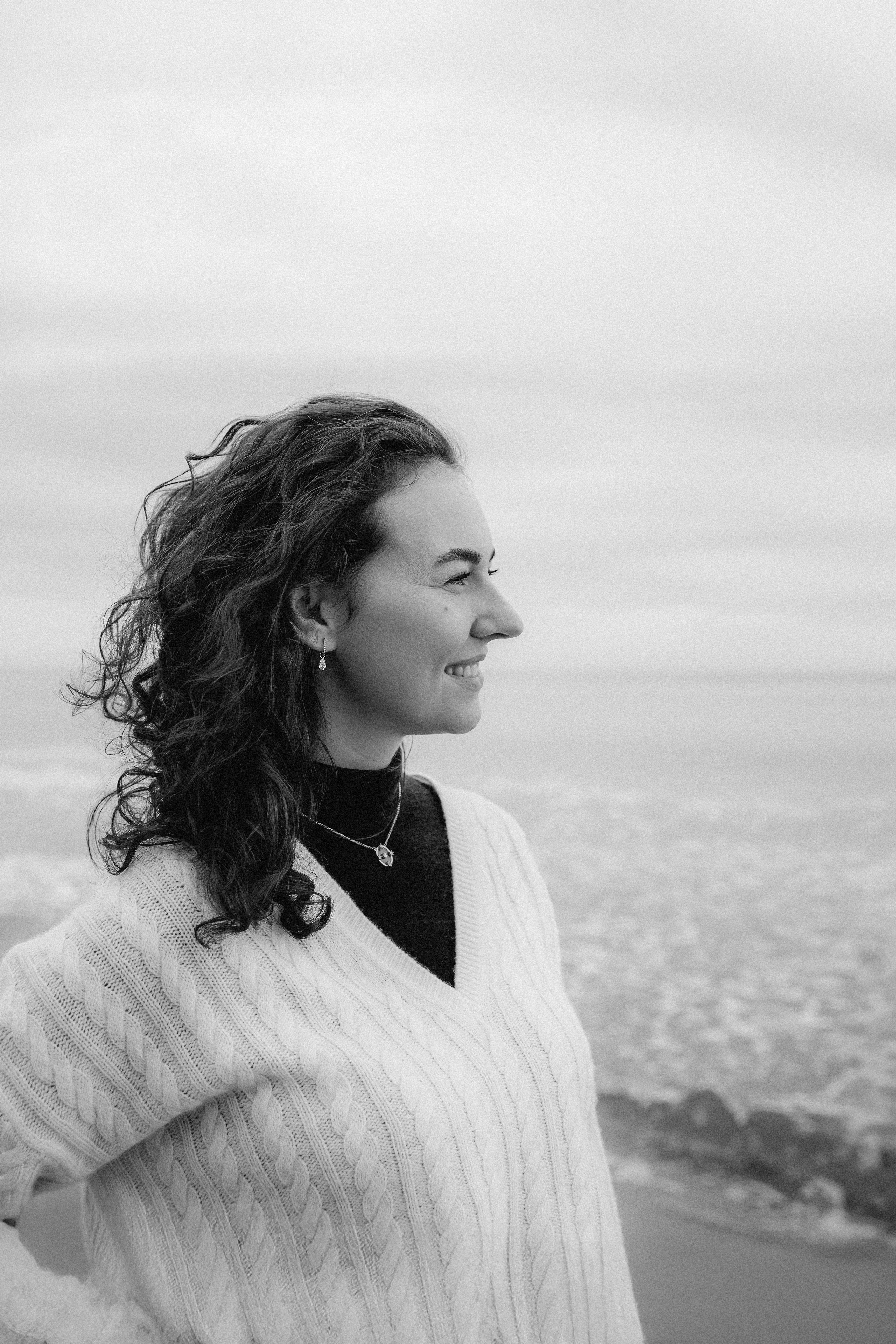 Женская фотосессия в Валенсии, Испания, с чёрно-белым портретом женщины в профиль у моря, с естественными кудрями, мягким прибрежным светом и спокойной средиземноморской атмосферой, передающей искренний и созерцательный момент — идеально для женской фотографии, портретных сессий, художественных чёрно-белых съёмок, лайфстайл-портретов и профессиональных женских фотосессий в Валенсии и по всей Испании.