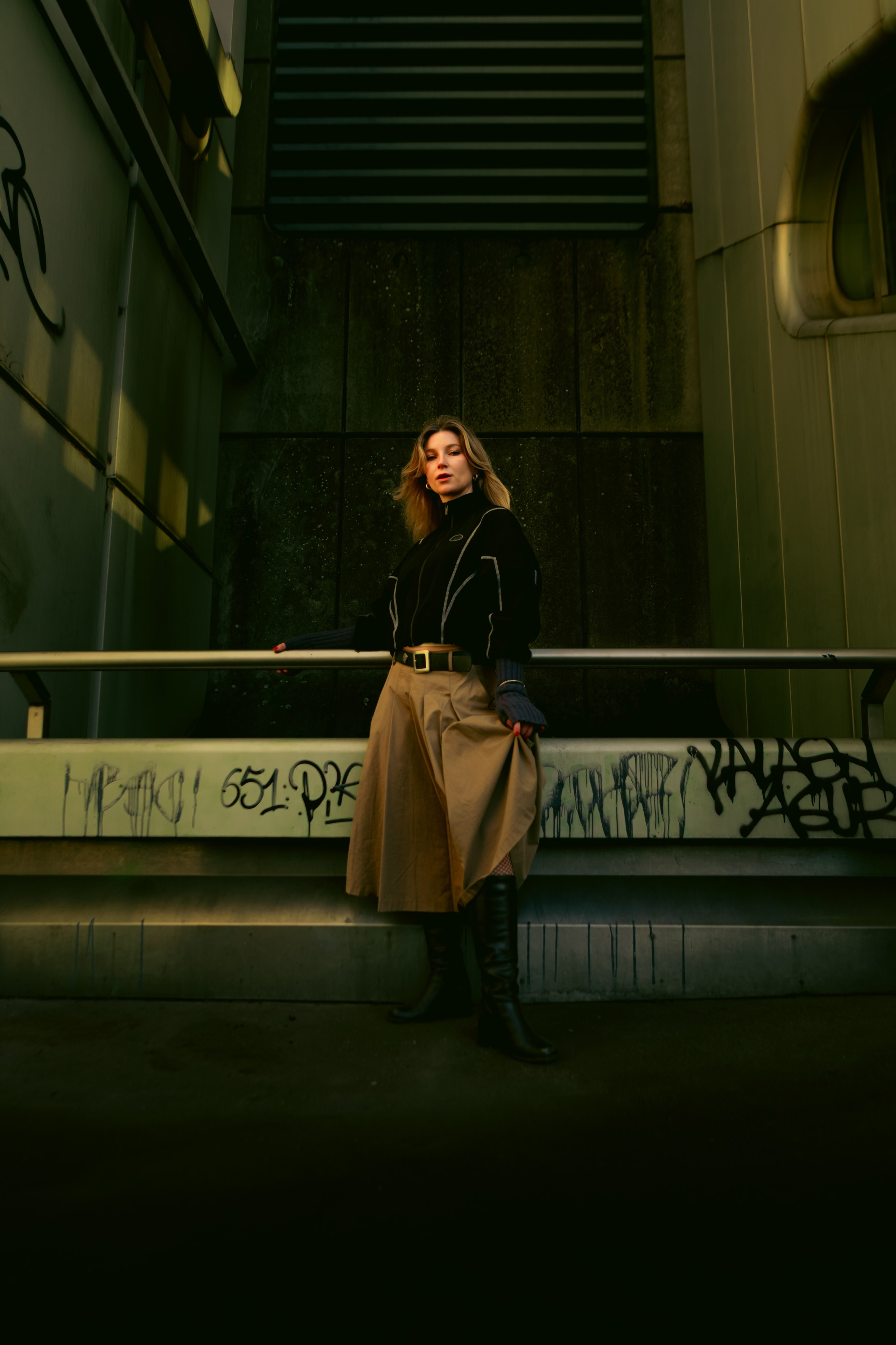 Atmospheric female portrait in Berlin with graffiti walls, urban architecture and dramatic lighting