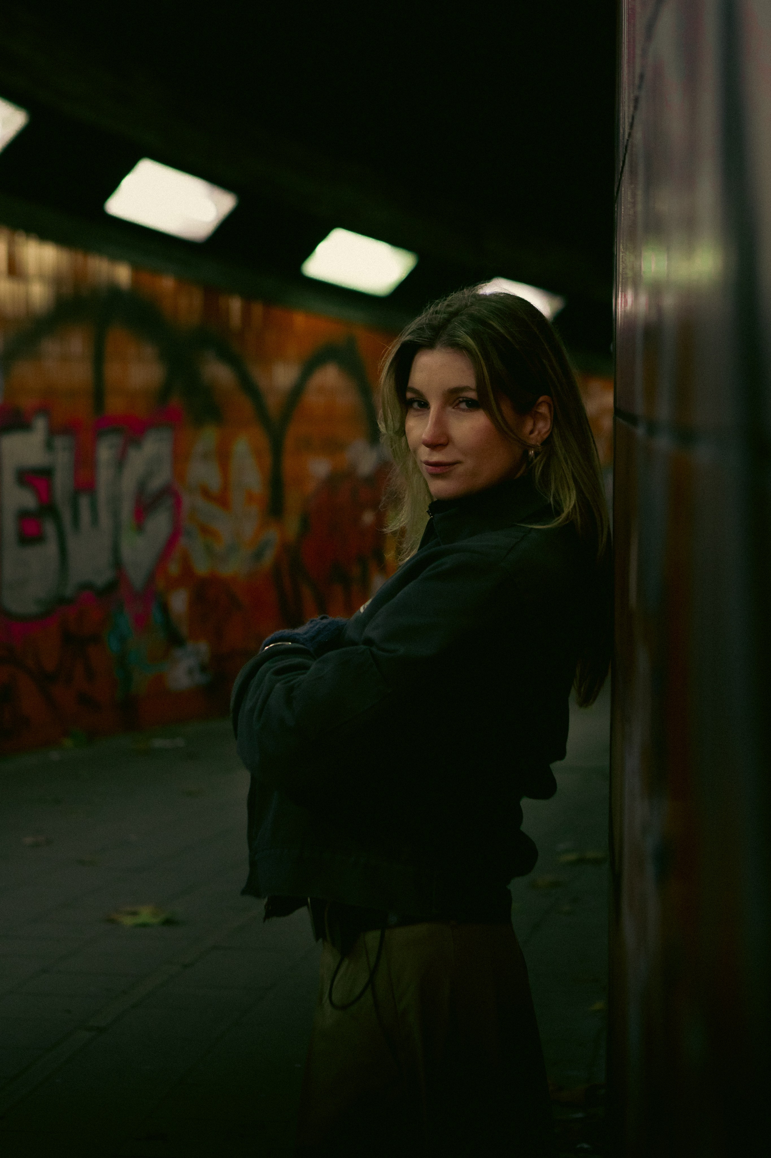 Editorial female portrait in a Berlin urban underpass surrounded by graffiti and strong shadows