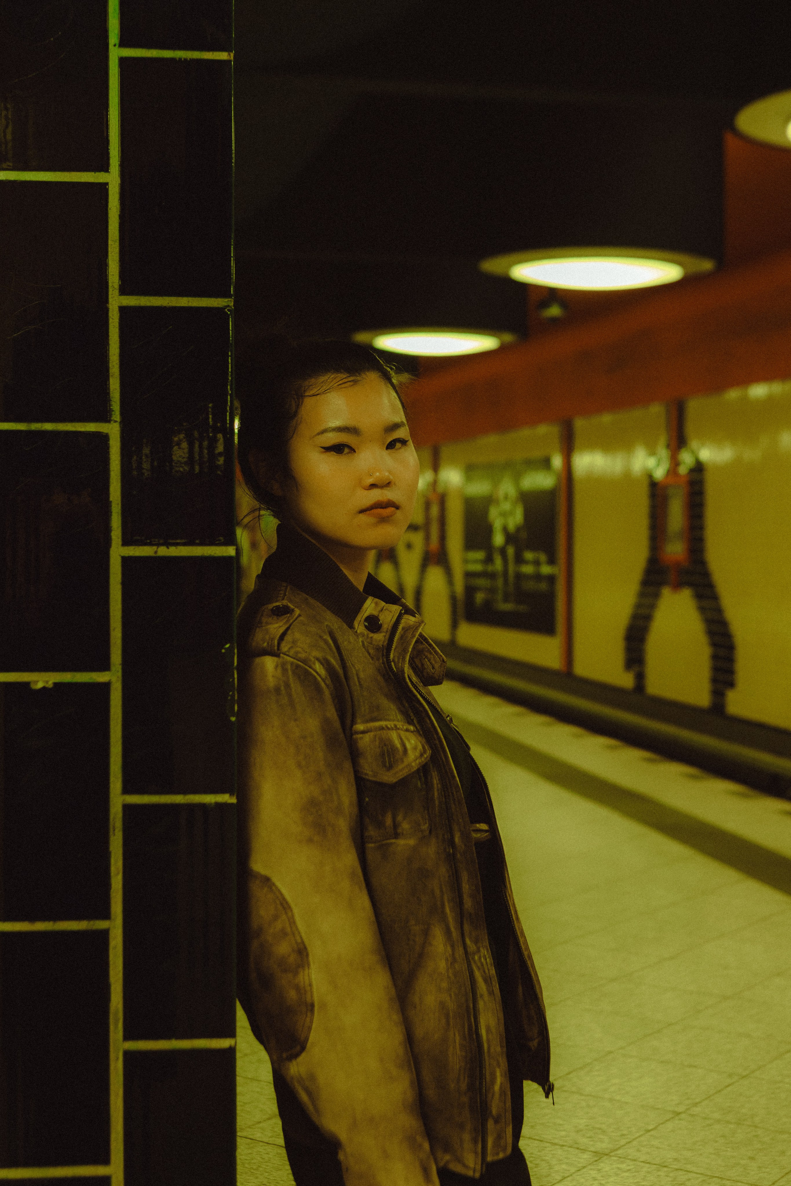 Woman standing beside a tiled column with a Berlin U-Bahn train in the background