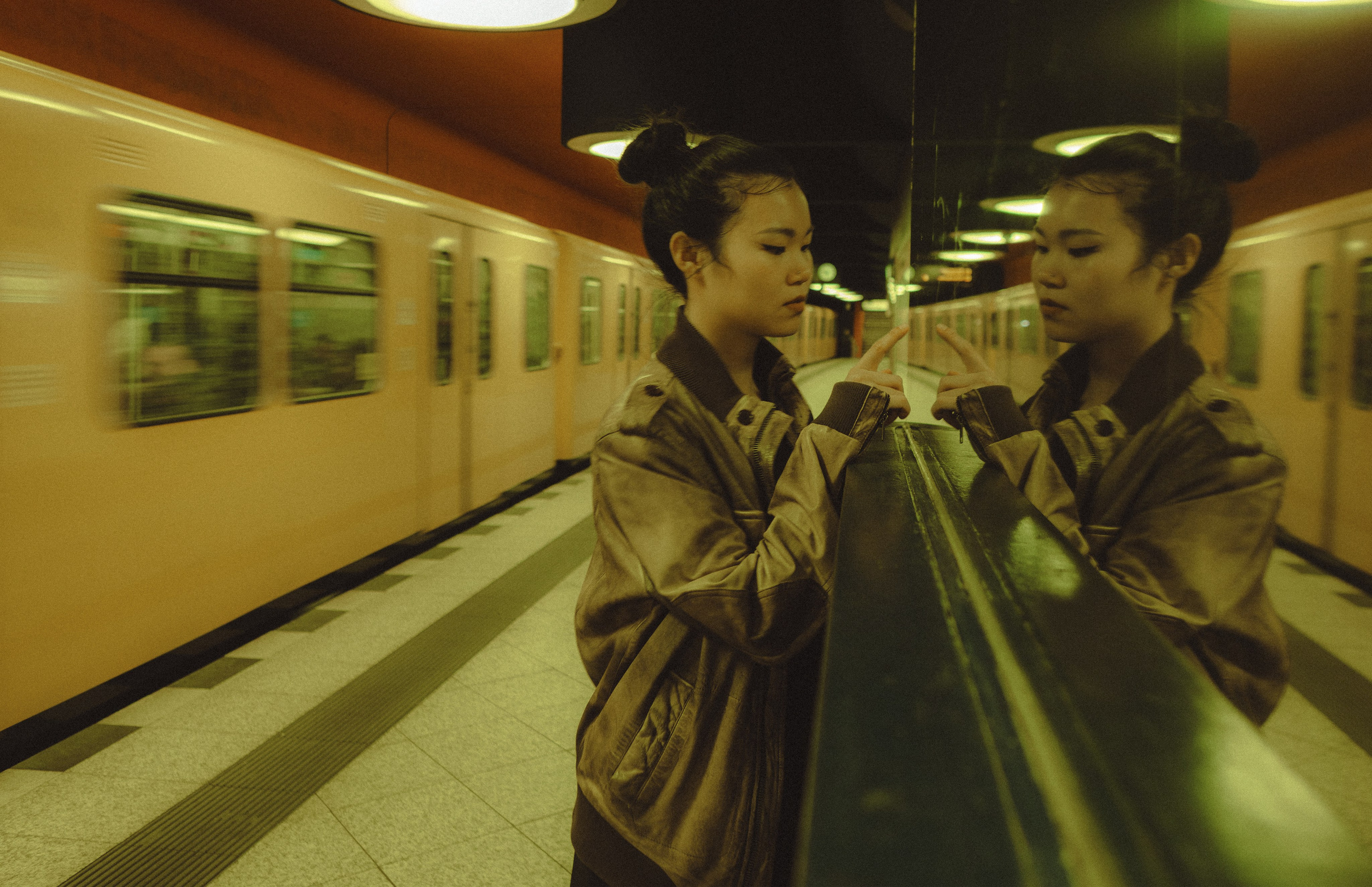 Woman standing beside a reflective column with a moving train in the background
