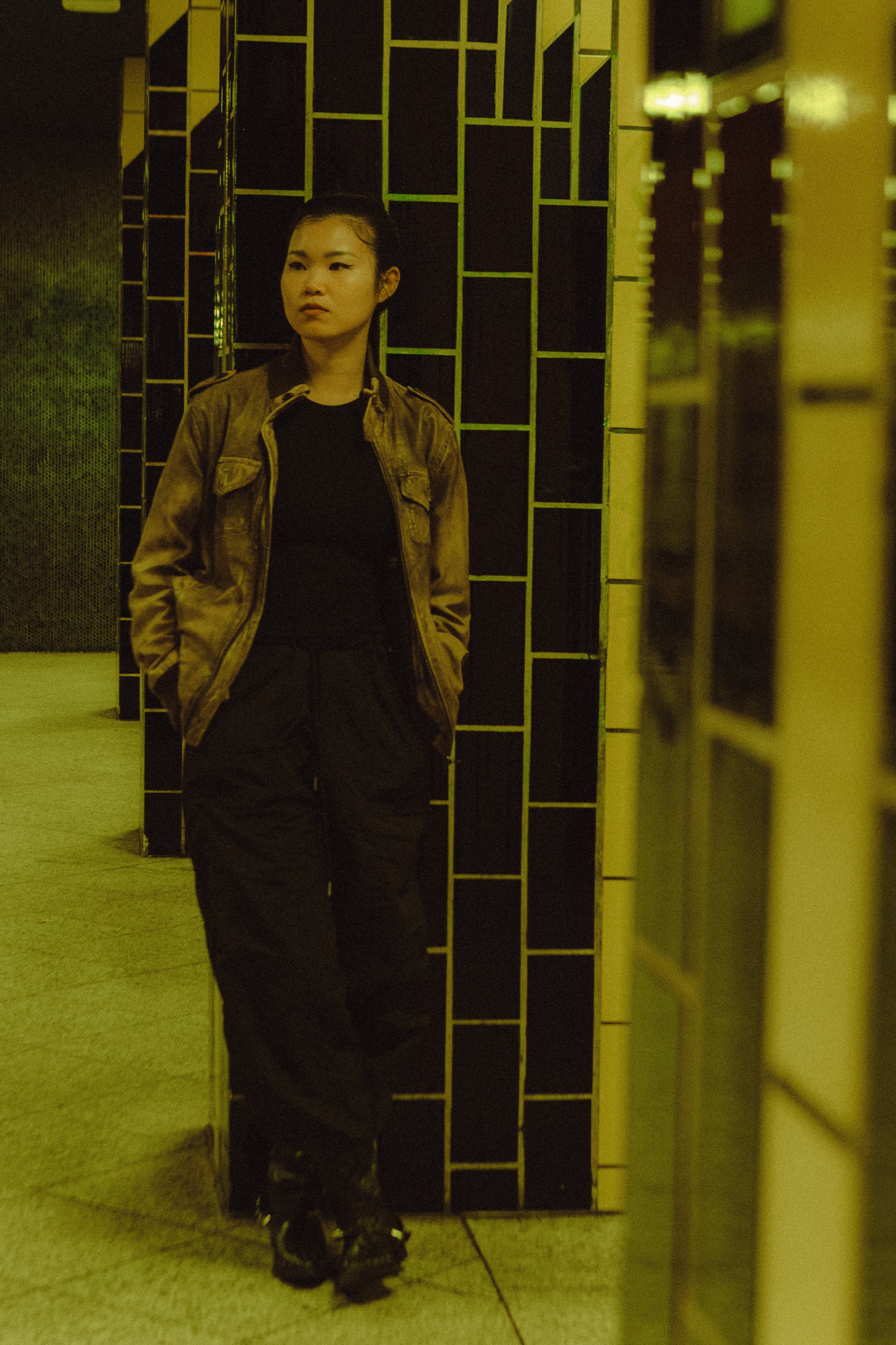 Woman standing against a dark tiled column at a Berlin U-Bahn station